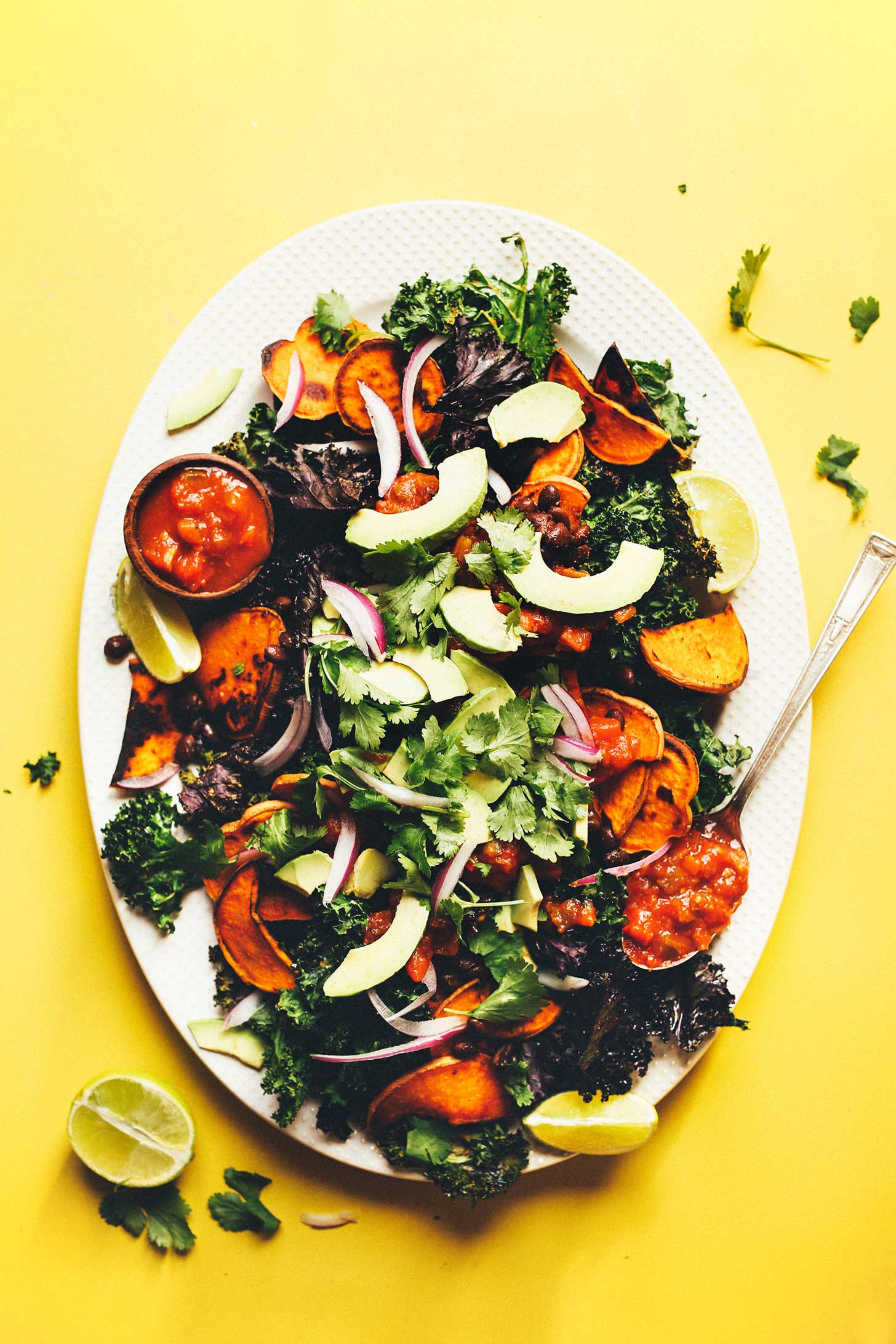 Ceramic platter filled with Kale Nachos with Black Beans, Sweet Potatoes, and Avocado