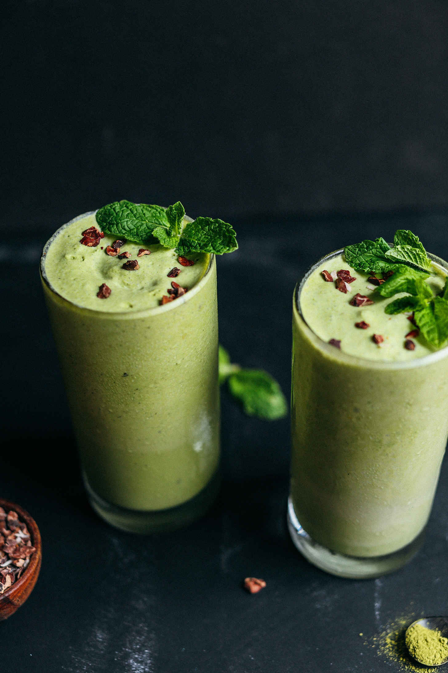 Two glasses of Mint Matcha Shakes topped with cacao nibs and mint leaves