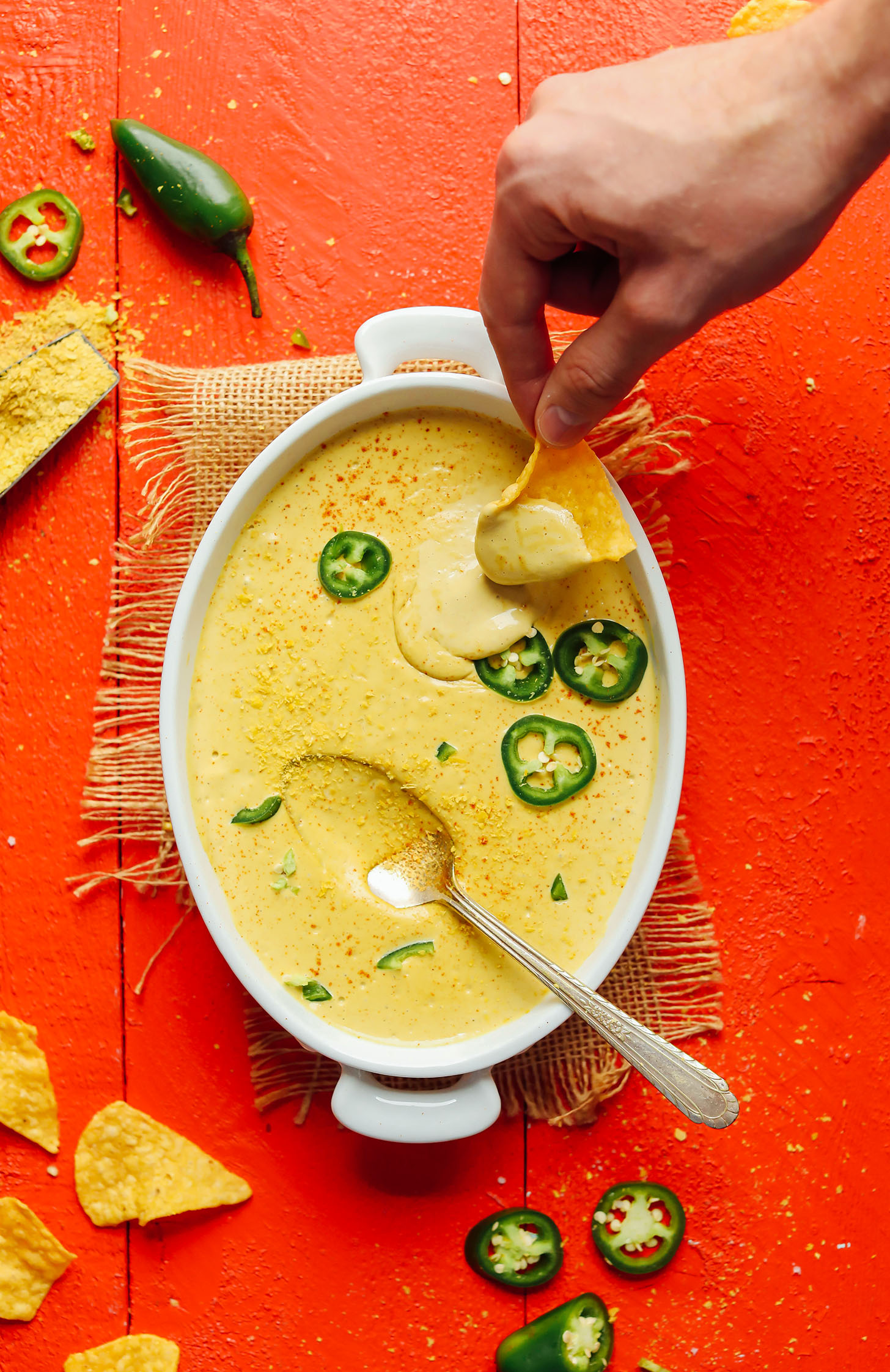 Dipping a tortilla chip into our Roasted Jalapeno Vegan Queso dip