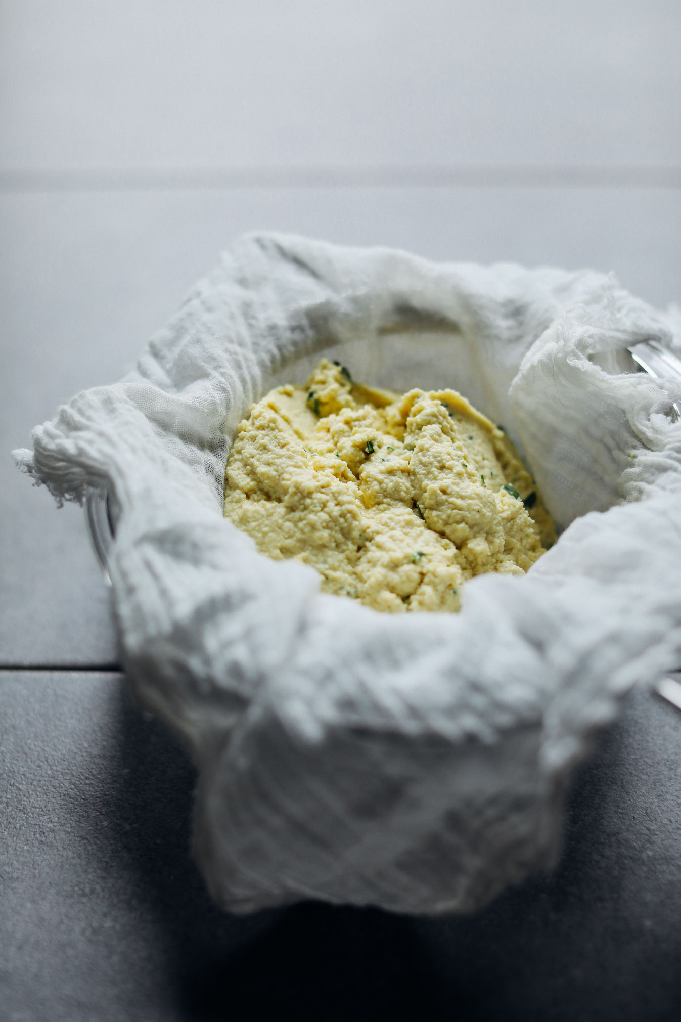 Glass bowl covered with a cheesecloth containing Macadamia Nut Herb Cheese