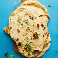 Cutting board with a stack of Vegan Naan topped with fresh parsley