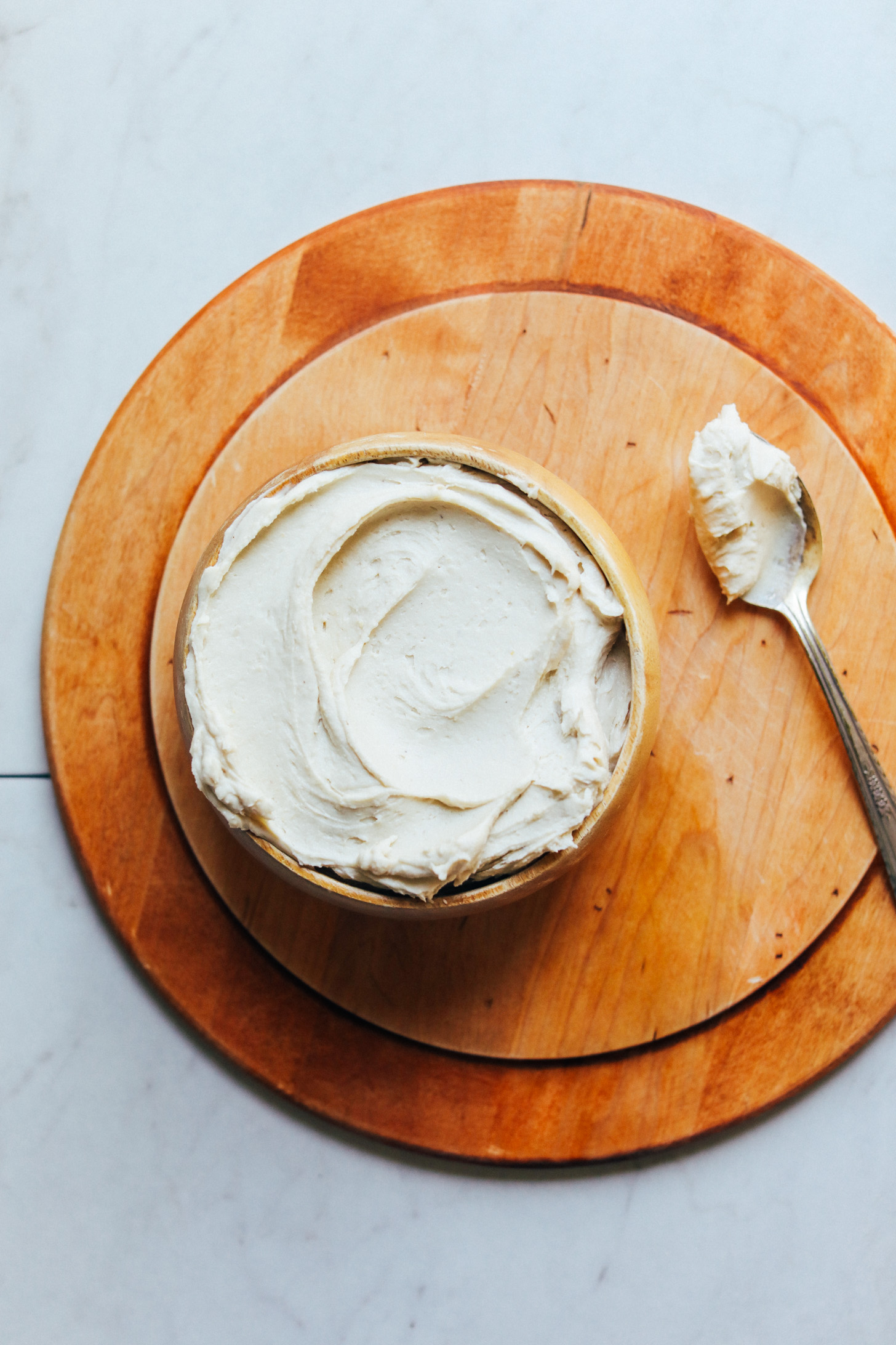 Bowl of spreadable vegan Cashew Buttercream Frosting on a cutting board