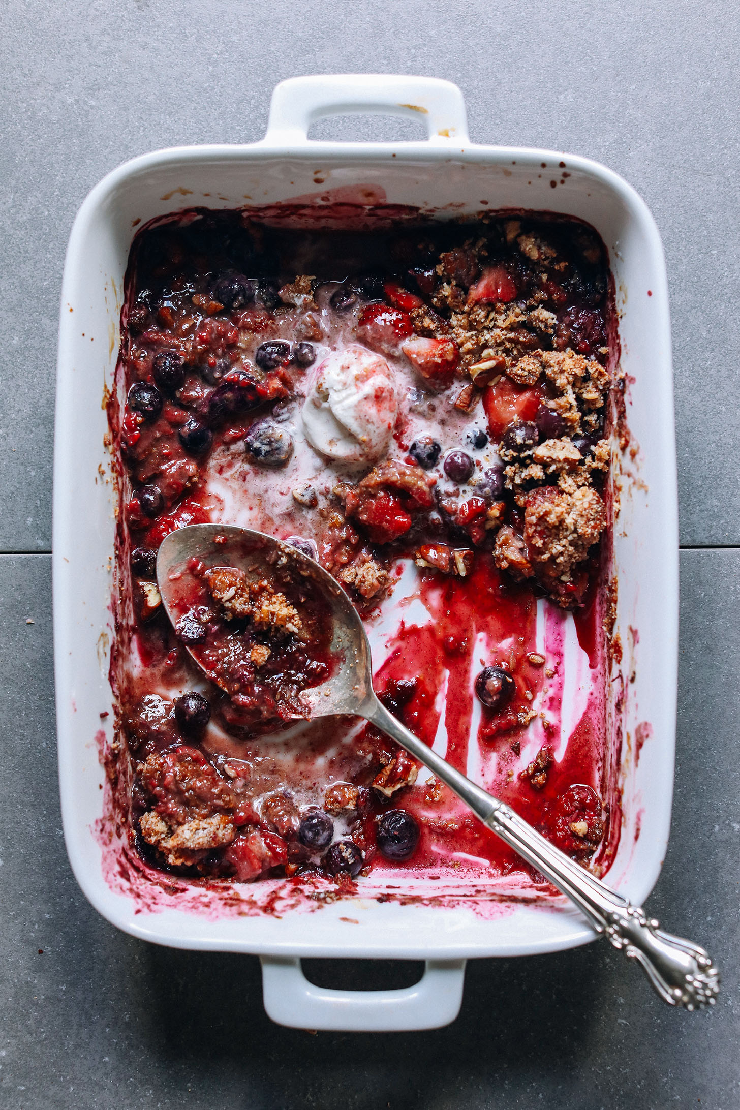 Warm Grain-Free Berry Crisp in a ceramic baking dish with a scoop of vegan ice cream