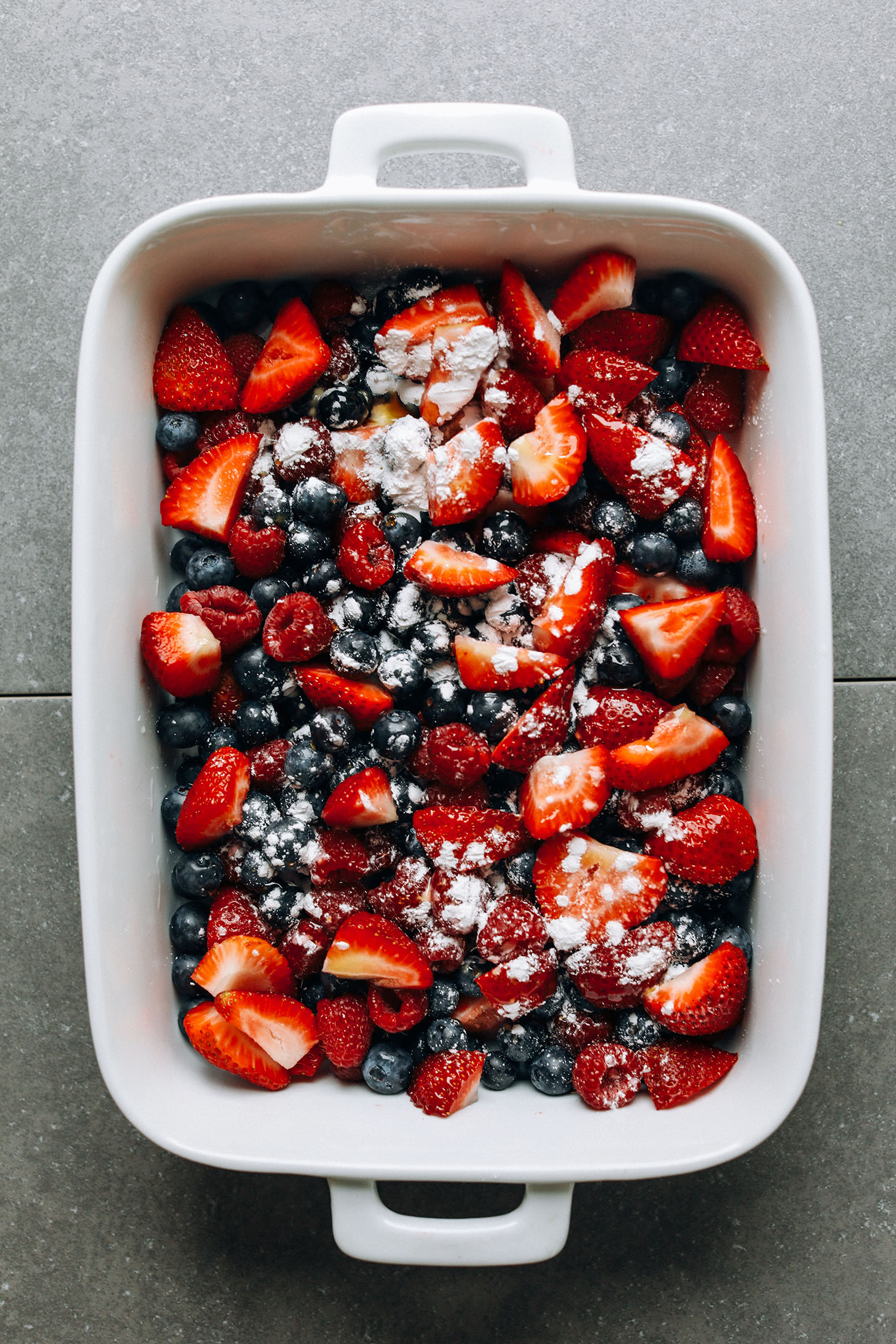 Fresh berries in a ceramic baking dish with arrowroot, lemon juice, and maple syrup