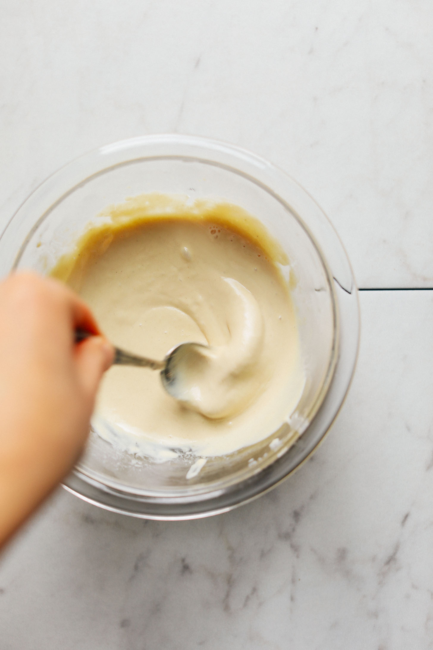 Stirring tahini dressing in a glass bowl for Raw Romaine Taco Boats