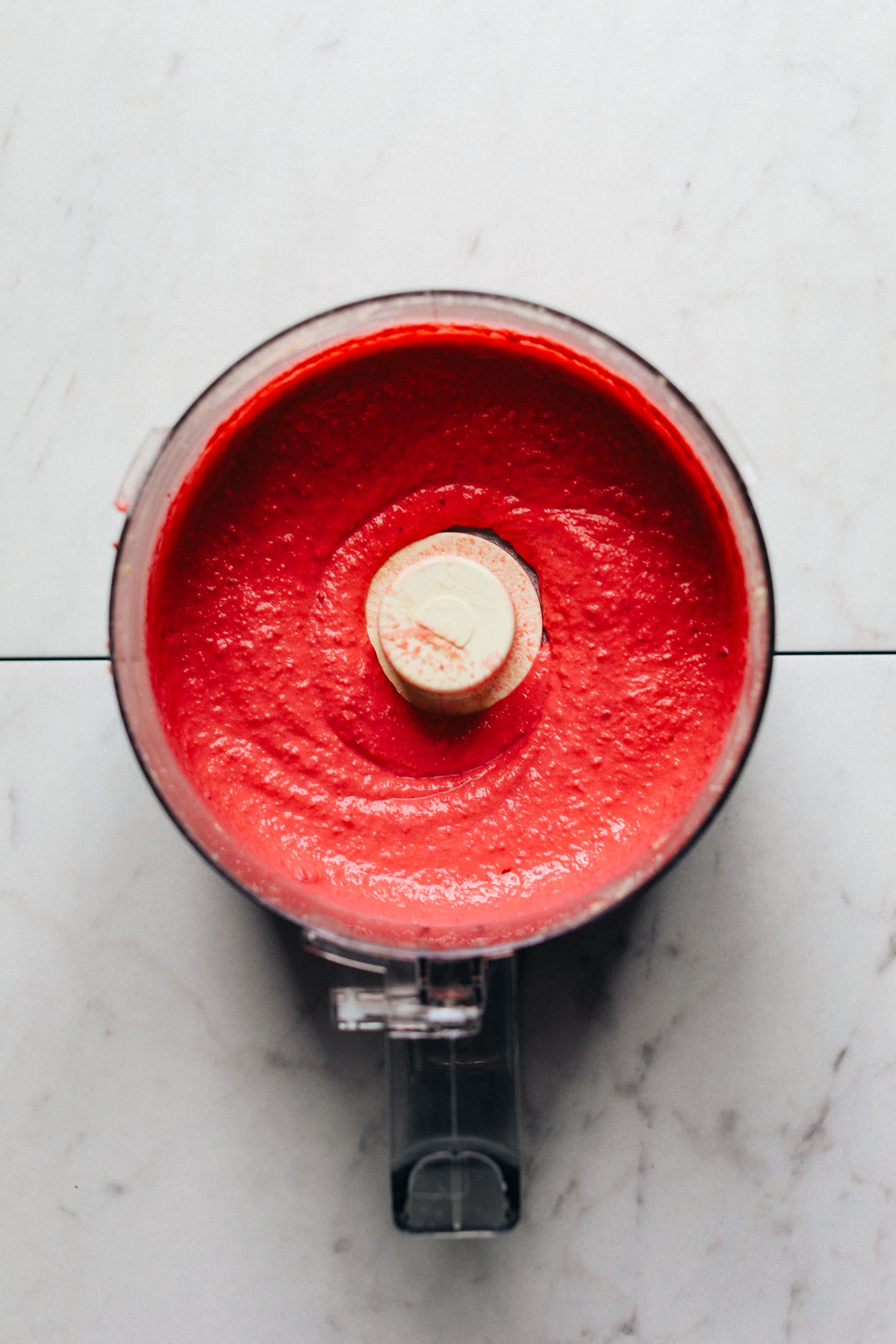 Food processor filled with vibrant beet hummus