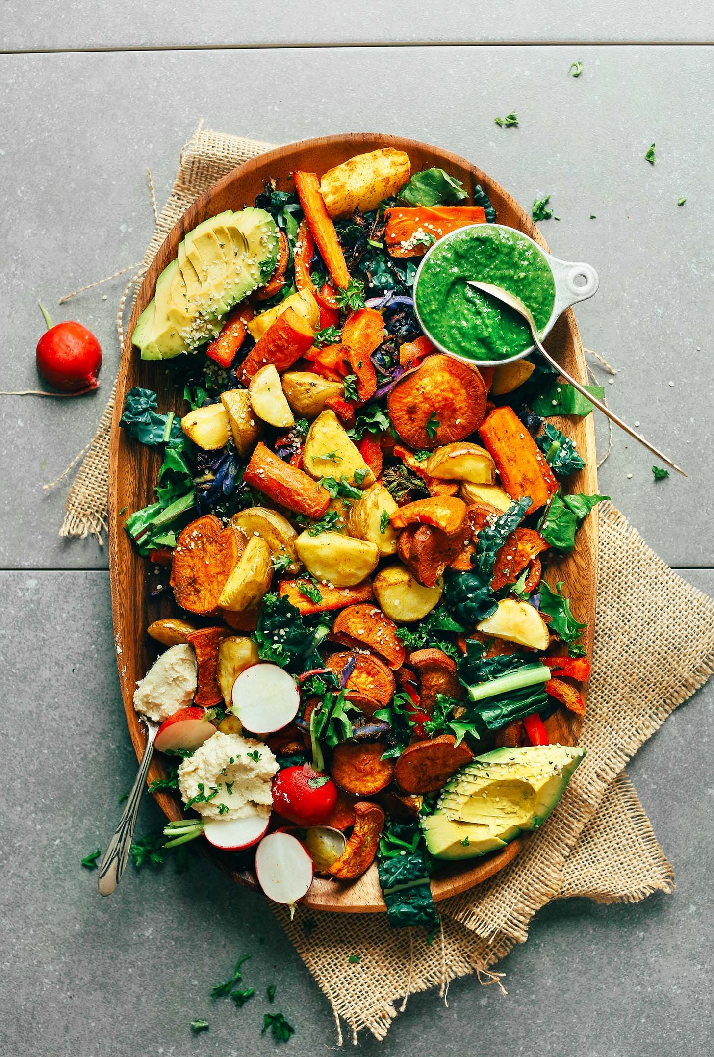 Wooden platter filled with Roasted Vegetable Salad & Chimichurri for a healthy plant-based meal