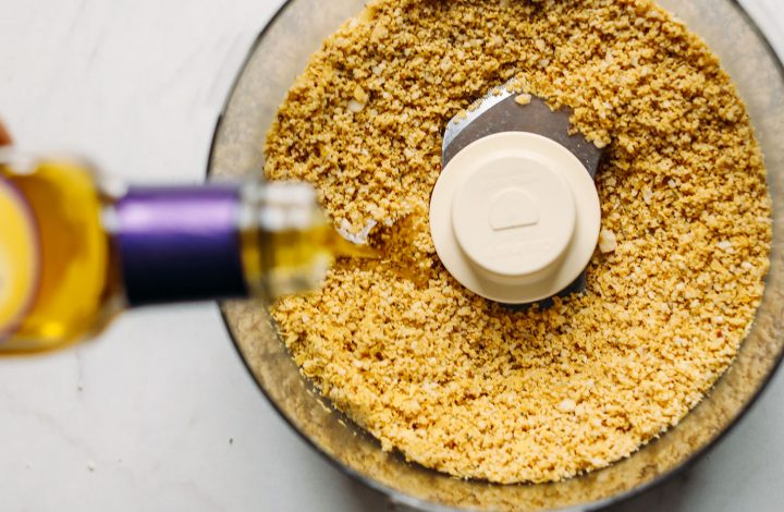 Pouring olive oil into the food processor for Vegan Parmesan Cheese