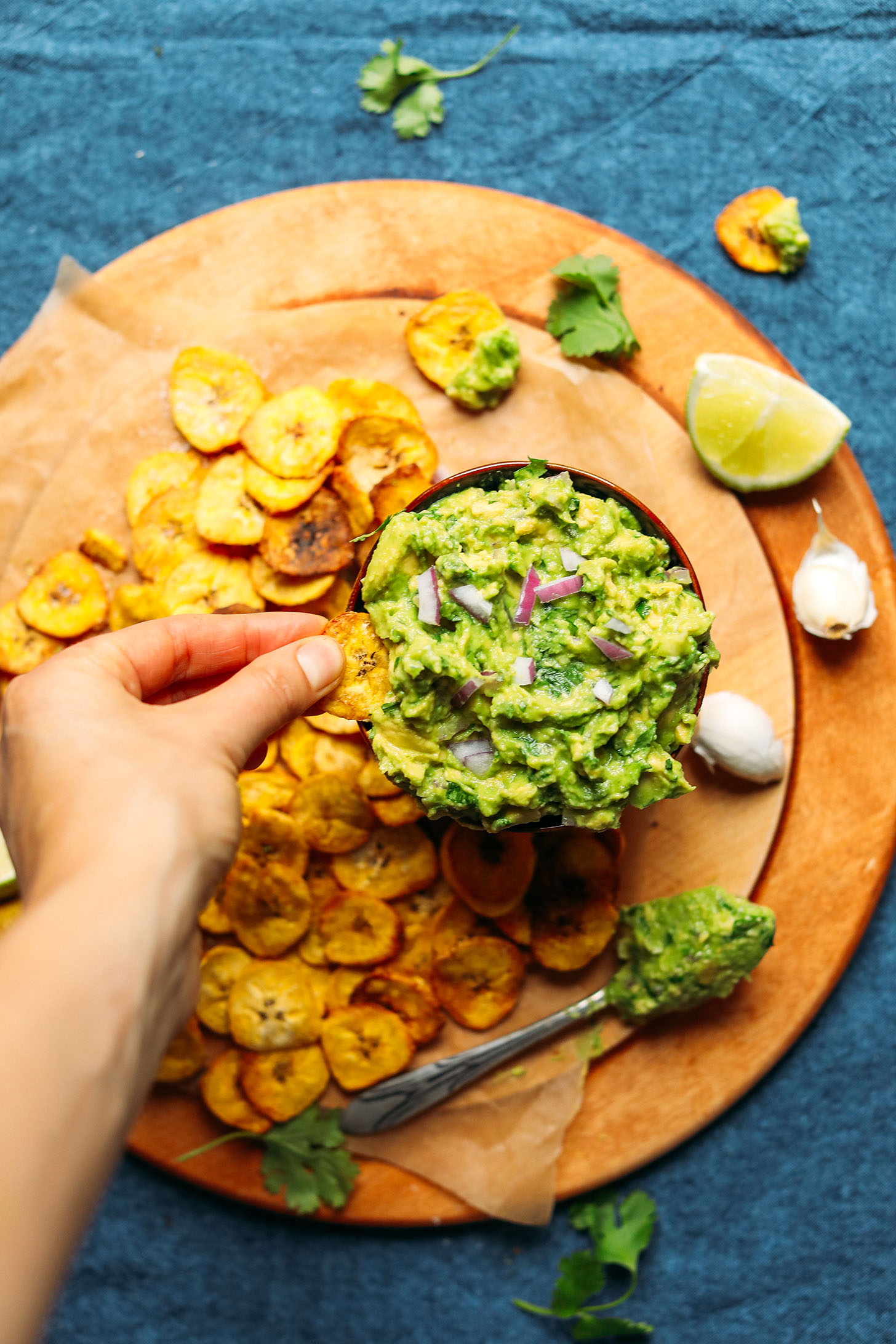 Grabbing a scoop of Garlicky Guacamole on a Crispy Baked Plantain Chip