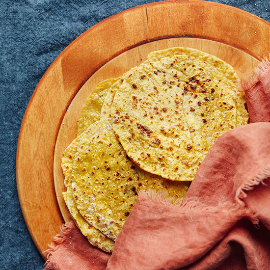 Homemade plantain tortillas wrapped in a linen on a cutting board