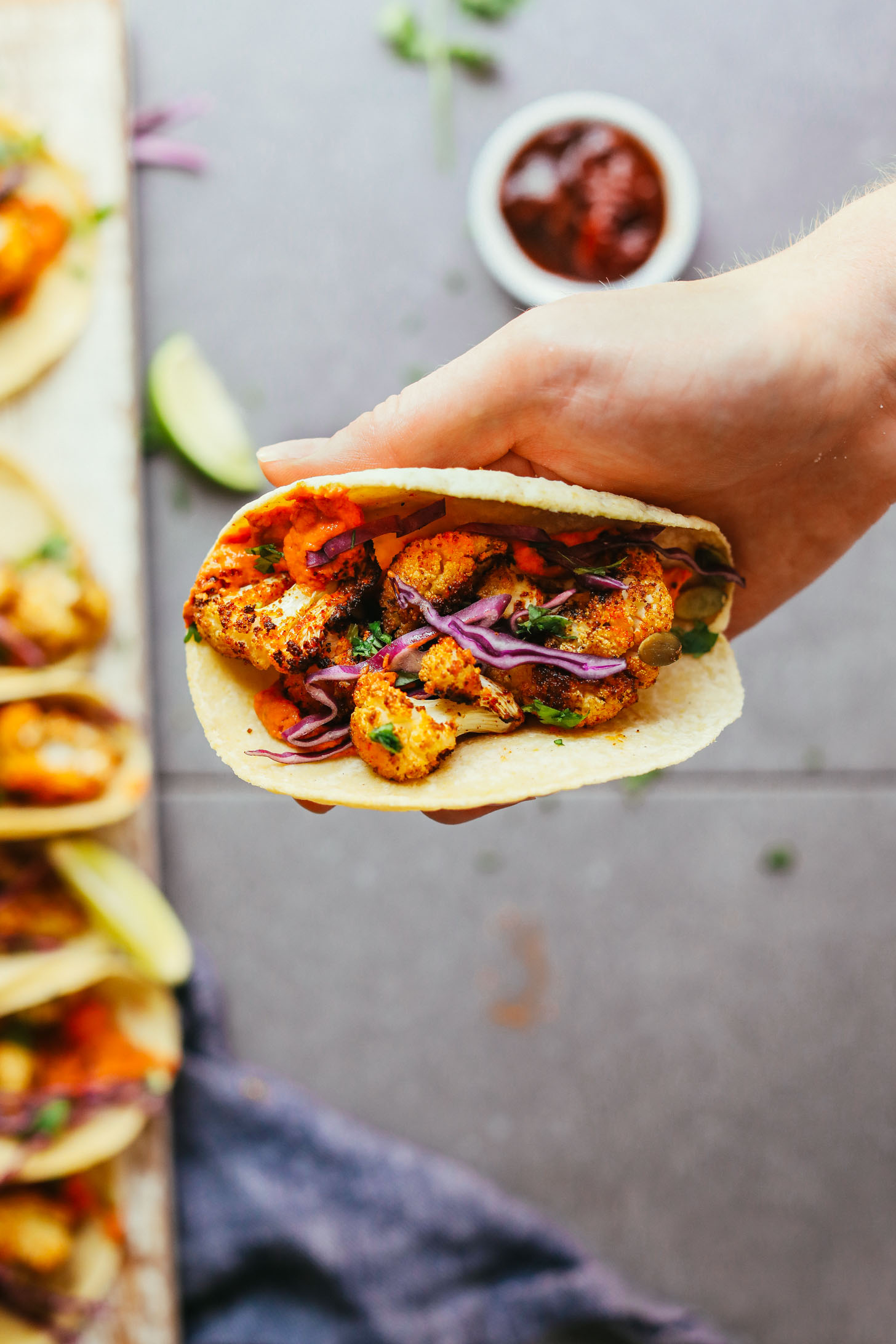 Holding up a vegan taco made with roasted cauliflower and adobo romesco