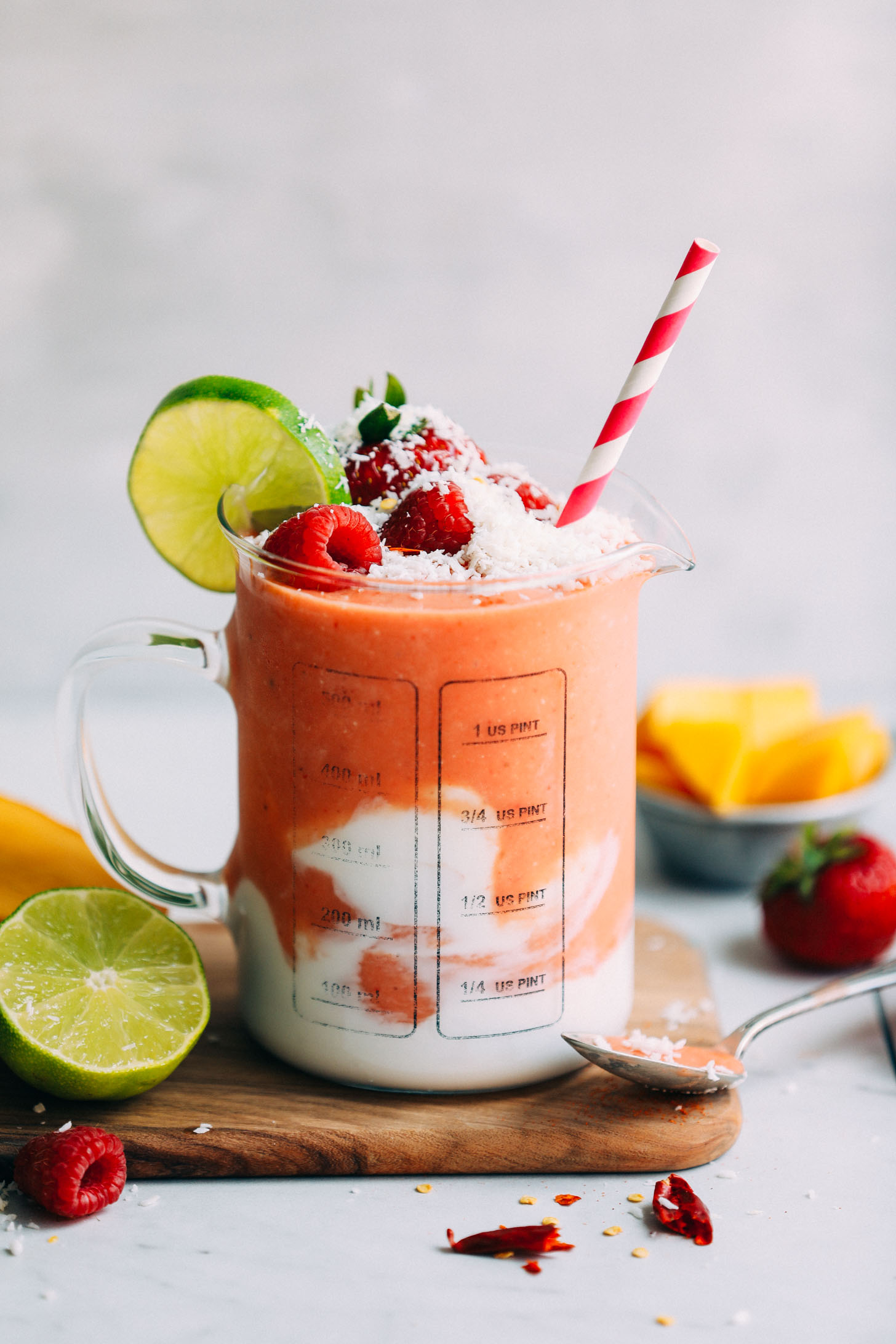 Serving jar with Gingery Mango & Berry Smoothie topped with fresh fruit and shredded coconut