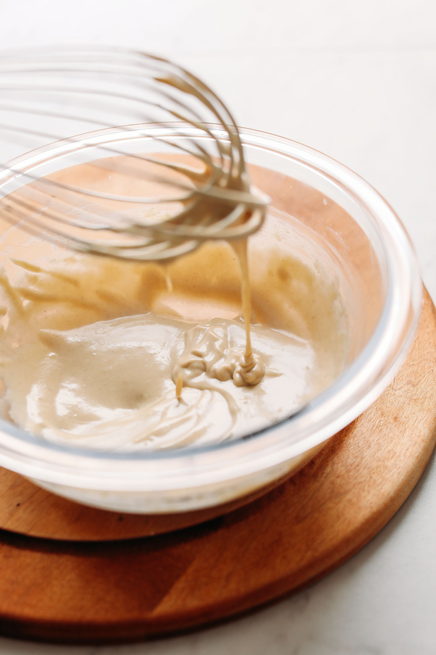Tahini Dressing dripping from a whisk into a bowl