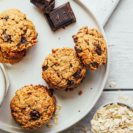 Oats, dark chocolate, and a plate of Healthy Oatmeal Chocolate Chip Cookies