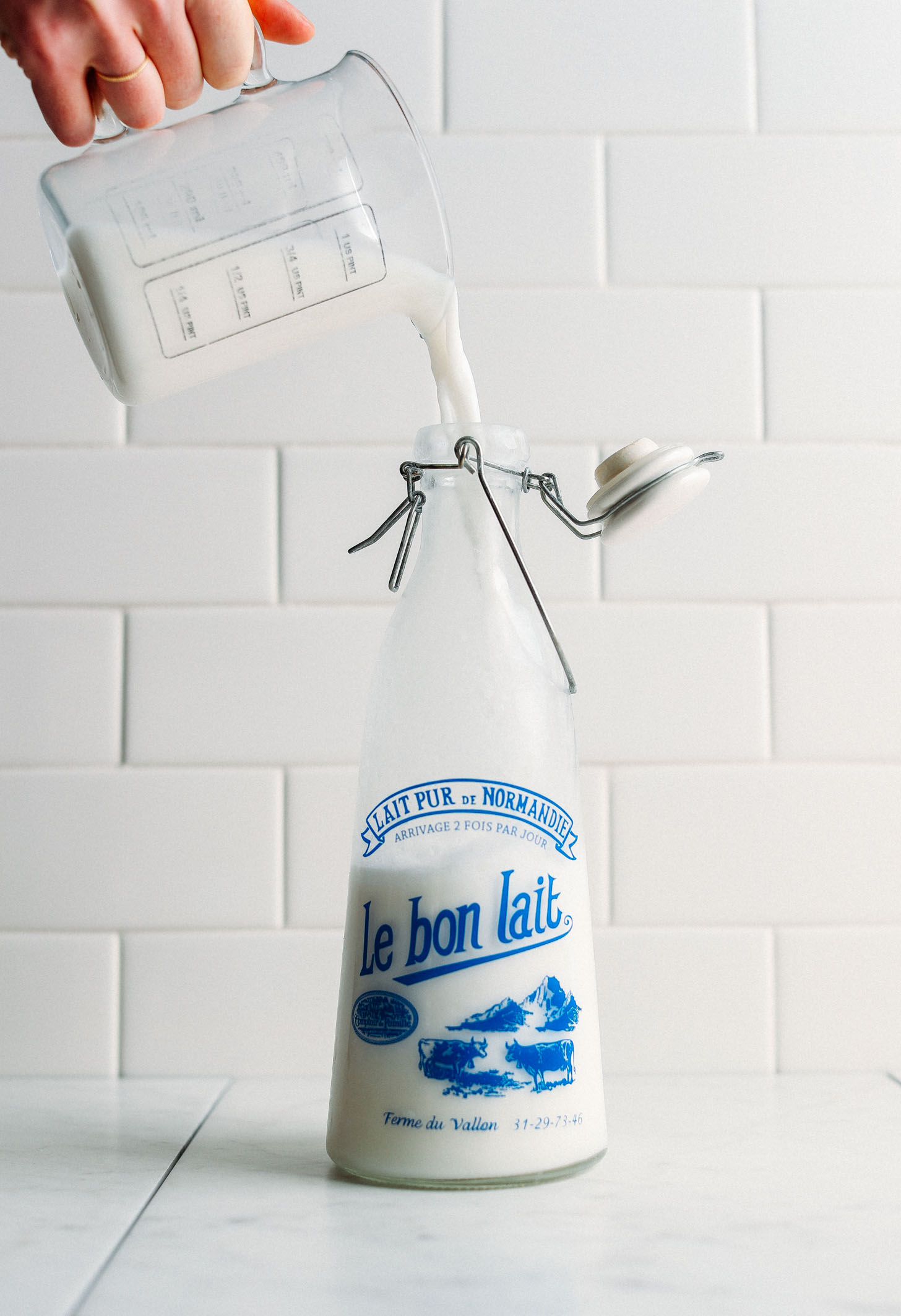 Pouring homemade dairy-free milk into an old-fashioned milk jug
