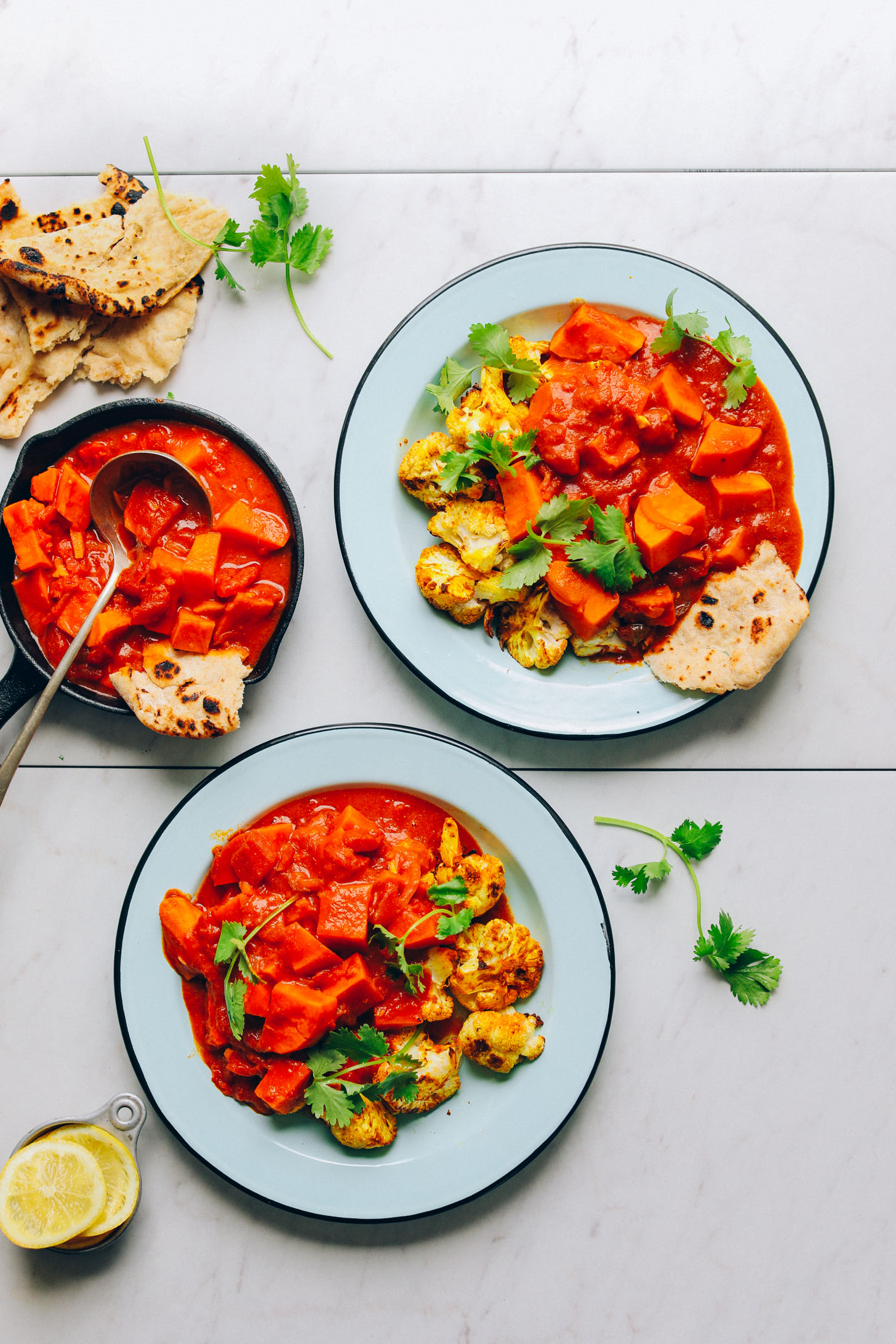 Bowls of Sweet Potato Cauliflower Curry with slices of pita bread