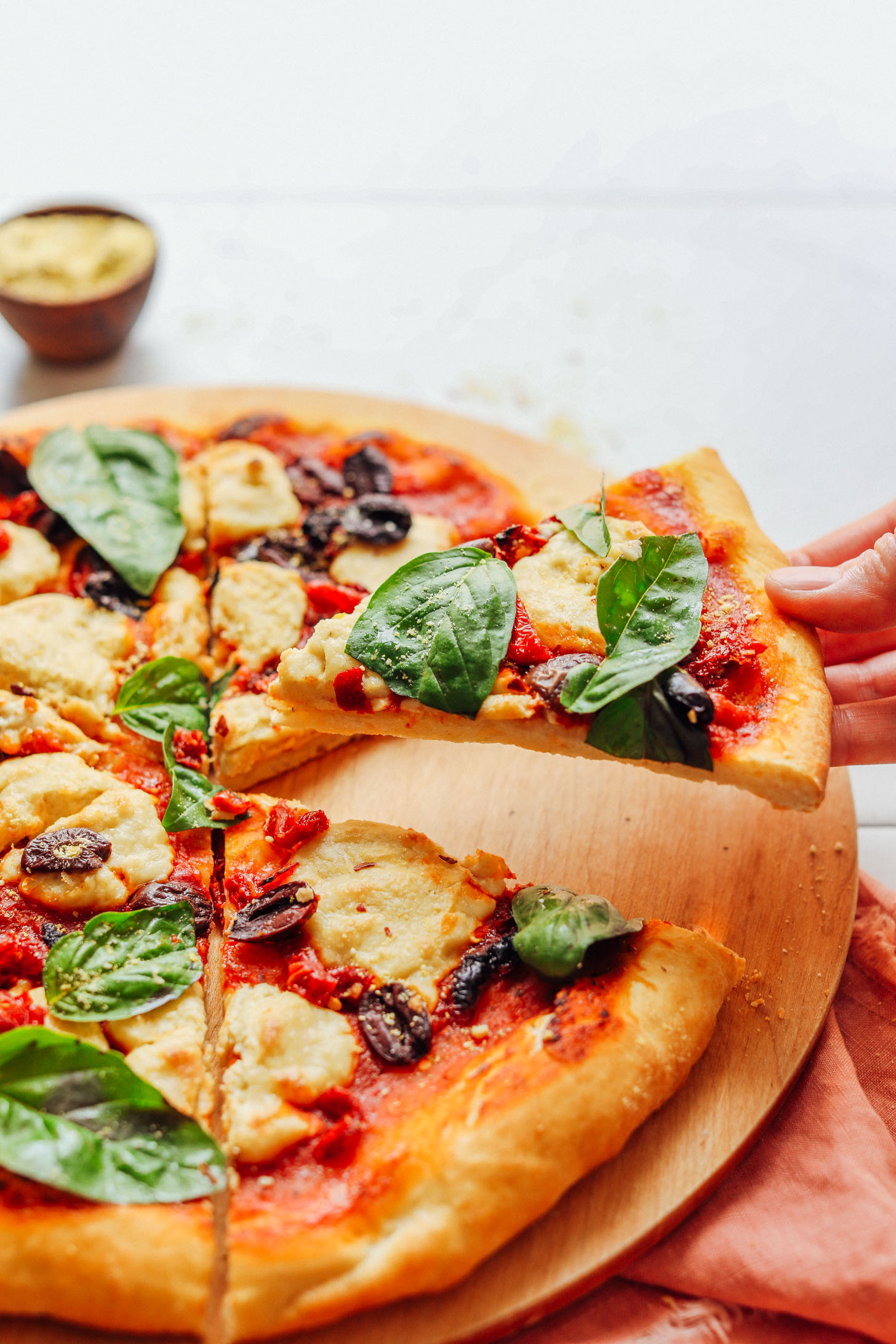 Grabbing a slice of gluten-free pizza made with homemade Vegan Mozzarella Cheese
