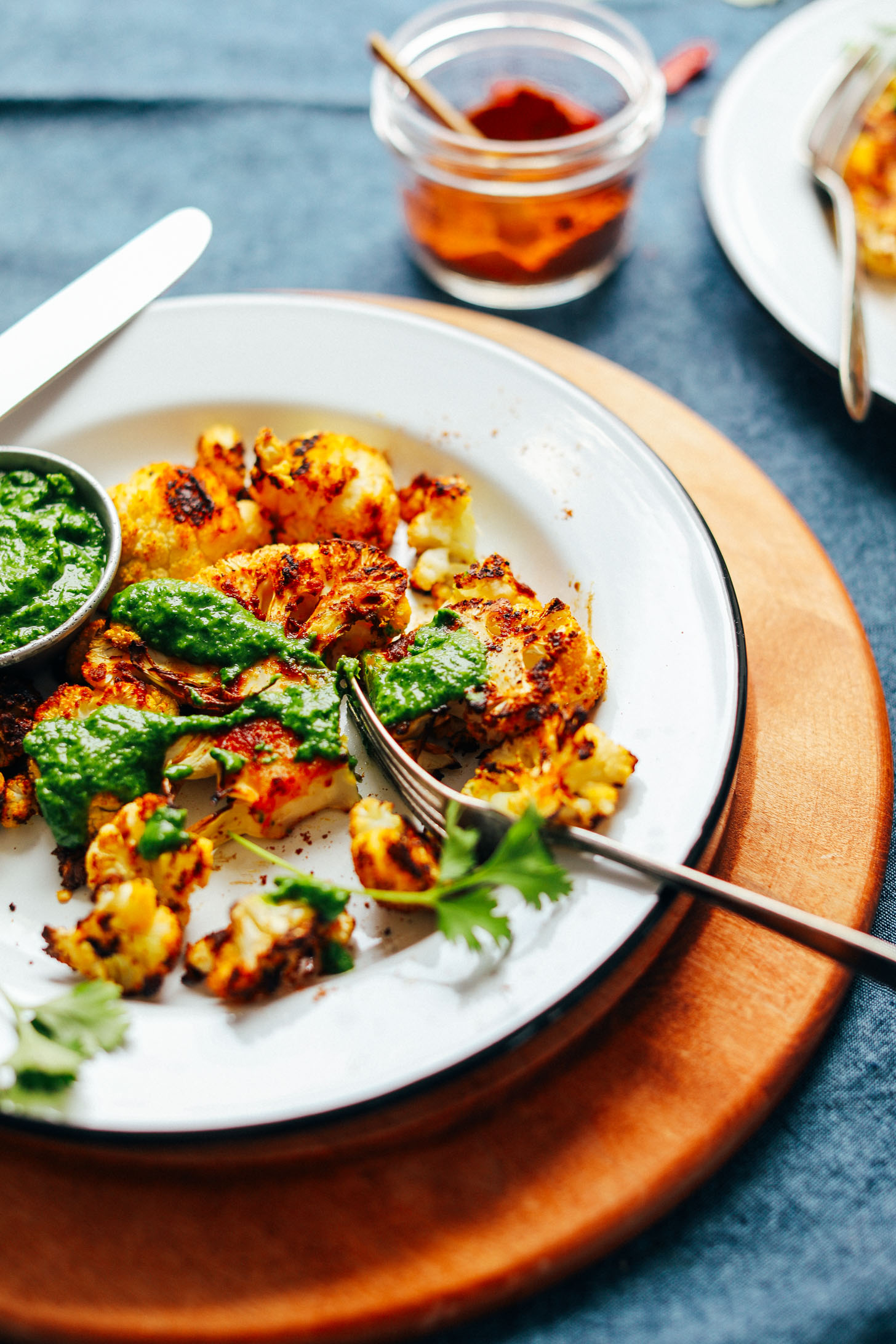 Using a fork to cut into a Shawarma Roasted Cauliflower Steak drizzled with green chutney