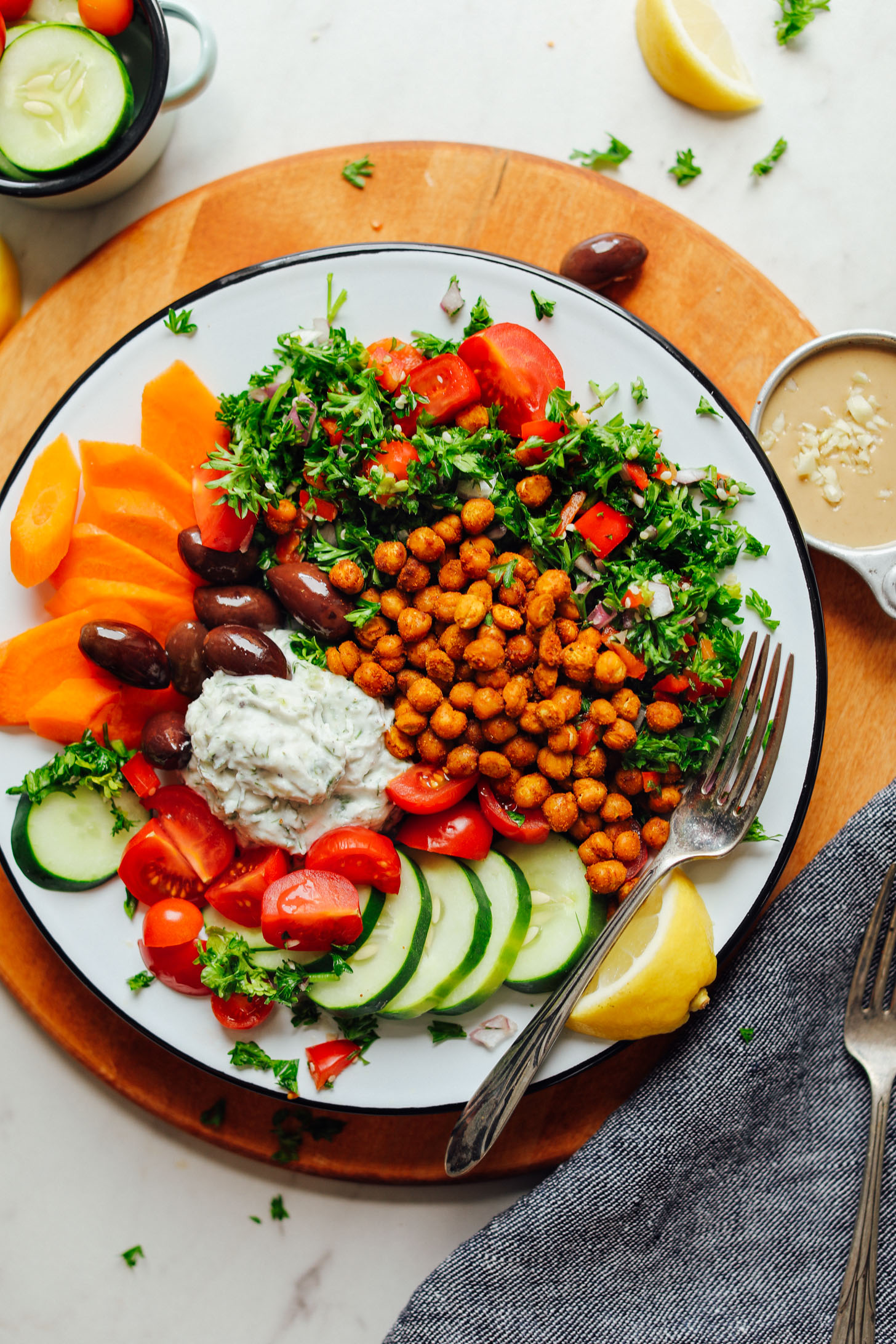 Cutting board topped with our Vegan Greek Bowl with Crispy Chickpeas, Vegan Tzatziki, and Veggies