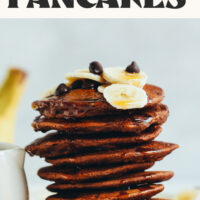 Stack of vegan gluten-free chocolate chocolate chip pancakes topped with sliced banana