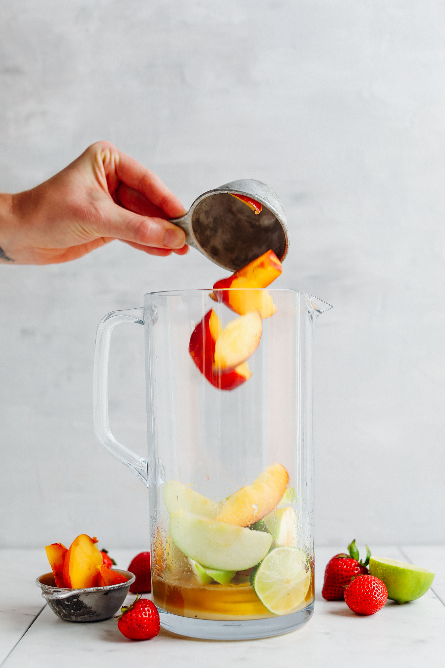 Tossing fresh peaches into a pitcher for Easy Traditional White Sangria
