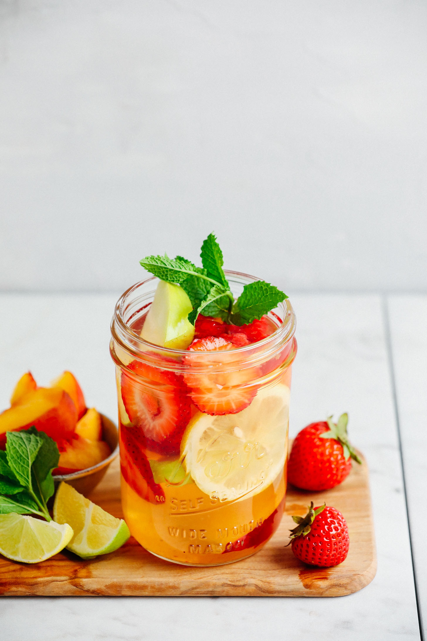 A small mason jar filled with Easy Traditional White Sangria loaded with fresh fruit and mint