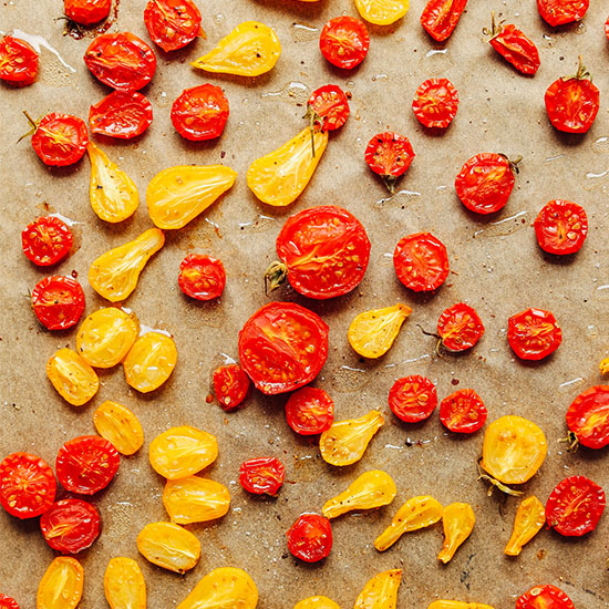 Parchment-lined baking sheet filled with slow roasted yellow and red cherry tomatoes