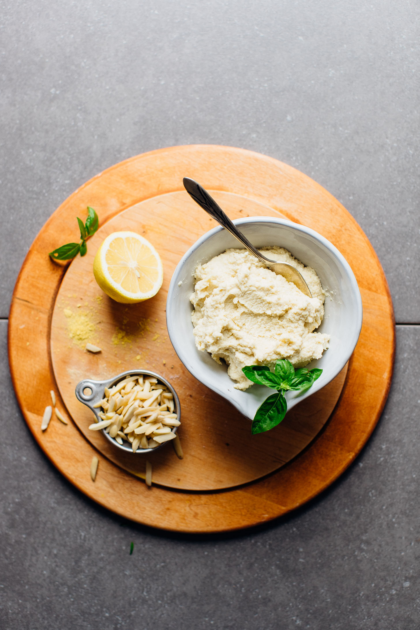 Bowl of delicious WHIPPED Vegan Ricotta Cheese on a cutting board with lemon and almonds