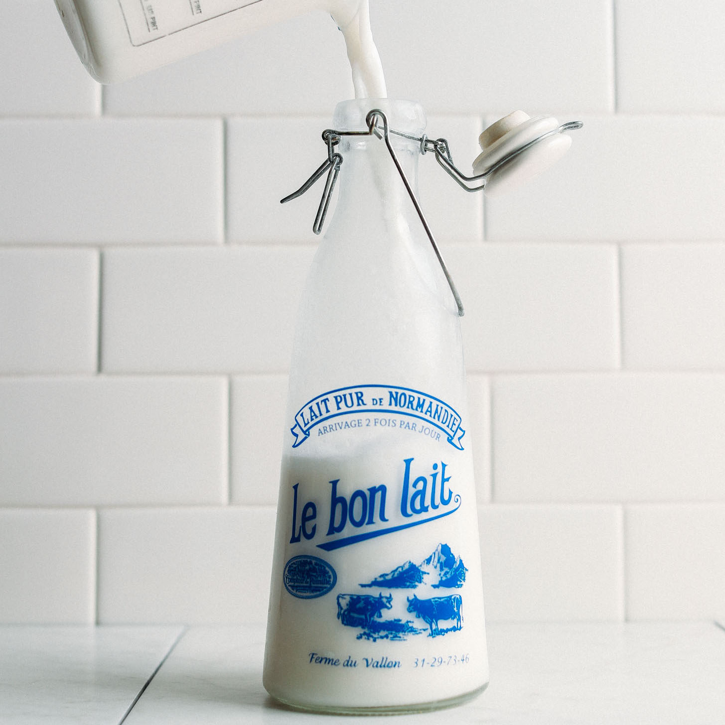 Pouring homemade coconut milk into an old-fashioned milk jug