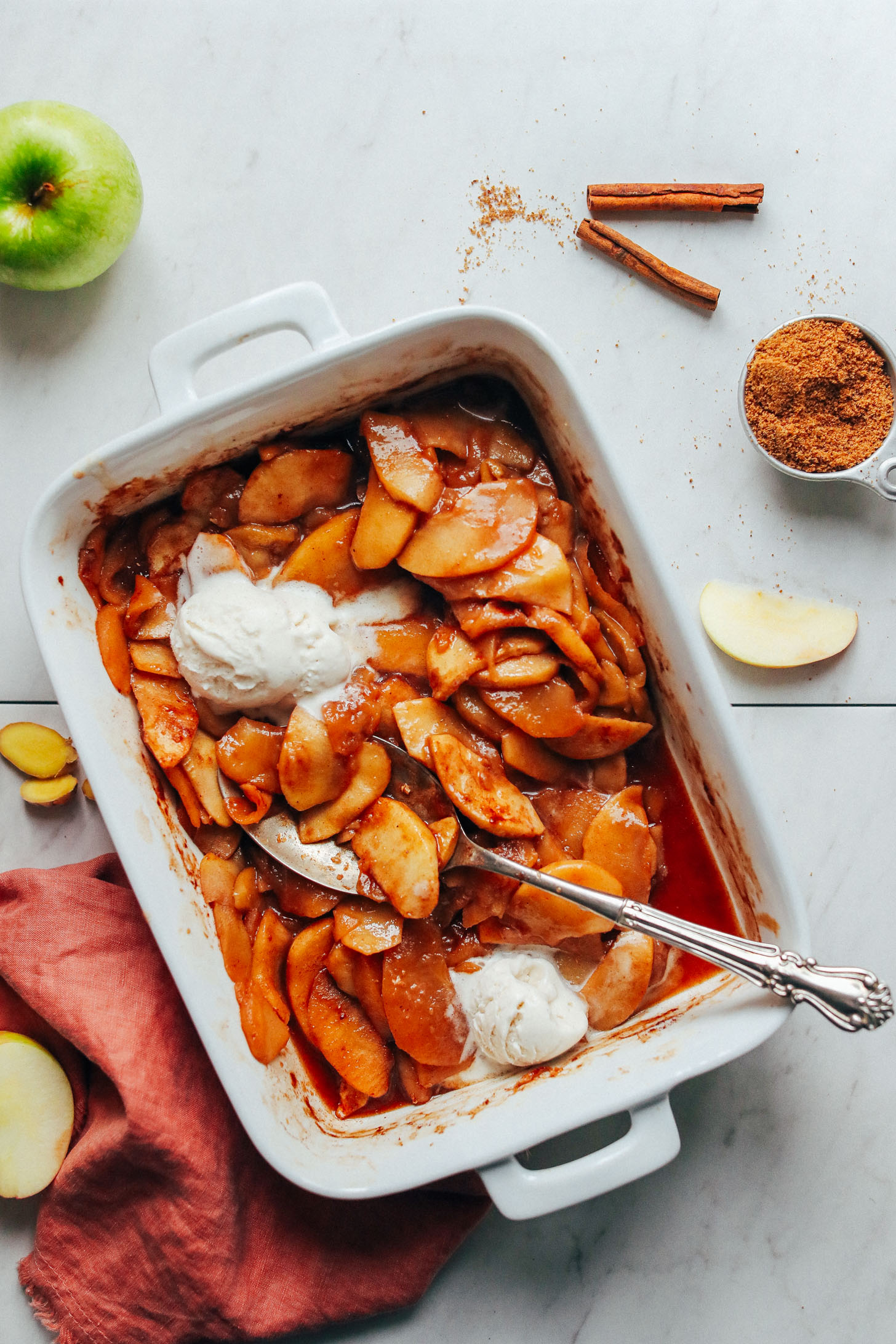 Ceramic baking dish filled with AMAZING Cinnamon Baked Apples and topped with vegan ice cream