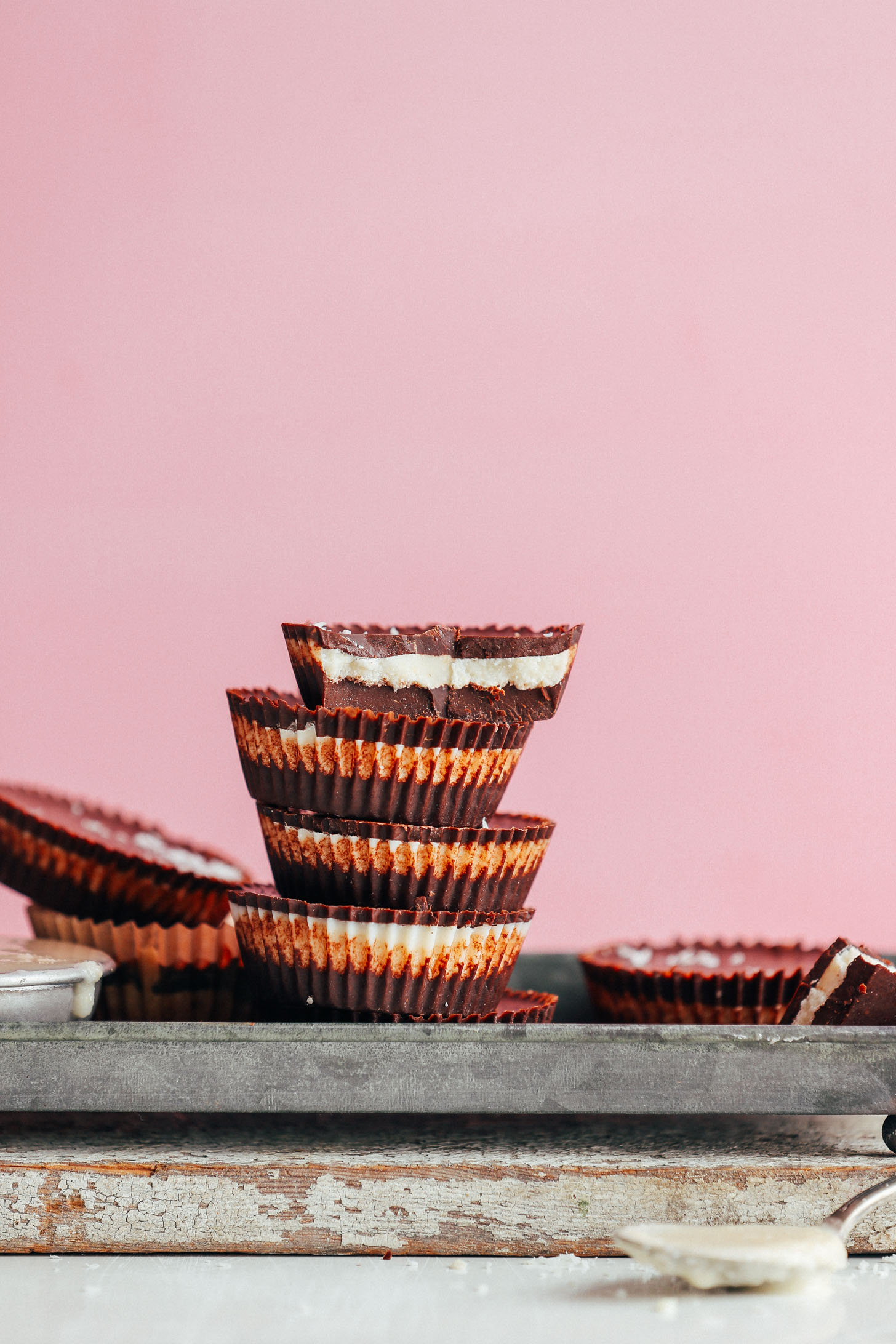 Stack of AMAZING vegan Coconut Butter Cups against a bright pink background