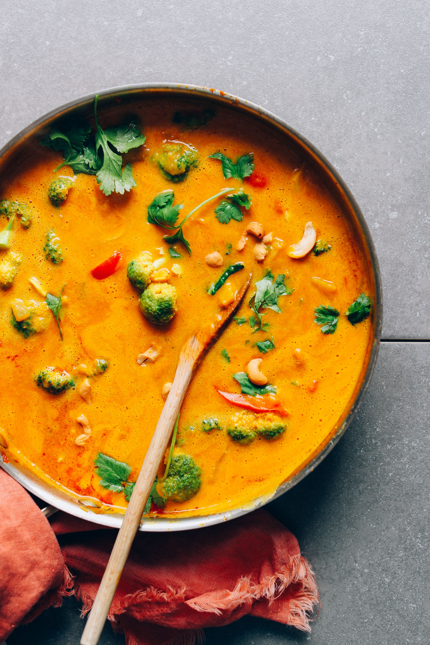 Stirring a pot of AMAZING Vegan Yellow Pumpkin Curry with colorful fresh vegetables