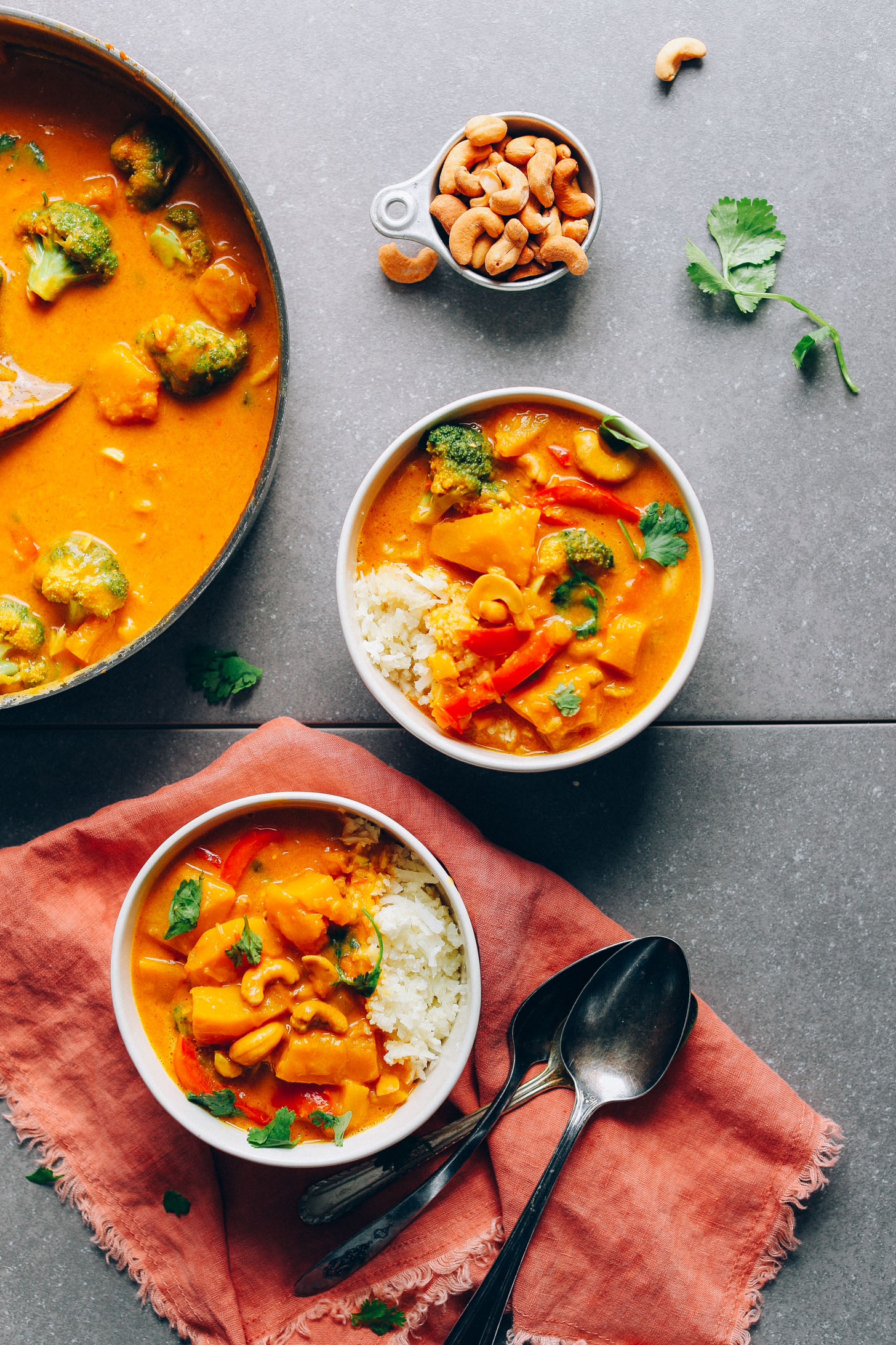 Two bowls of rice and Yellow Pumpkin Curry with a side of cashews for garnishing