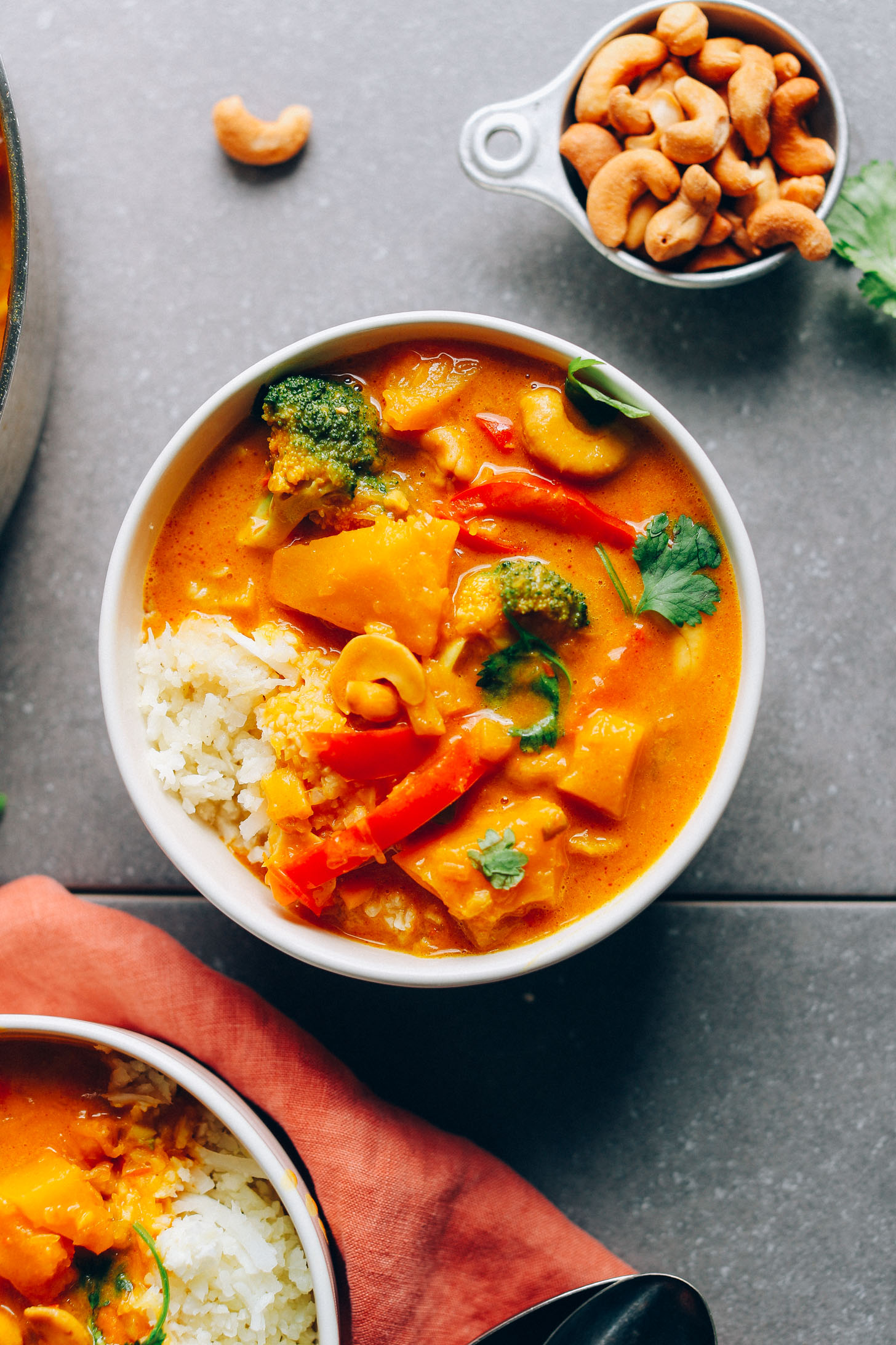 Top down shot of a bowl of gluten-free vegan Yellow Pumpkin Curry served with rice and cashews