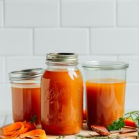 Close up shot featuring three jars of the best homemade gluten-free vegetable broth