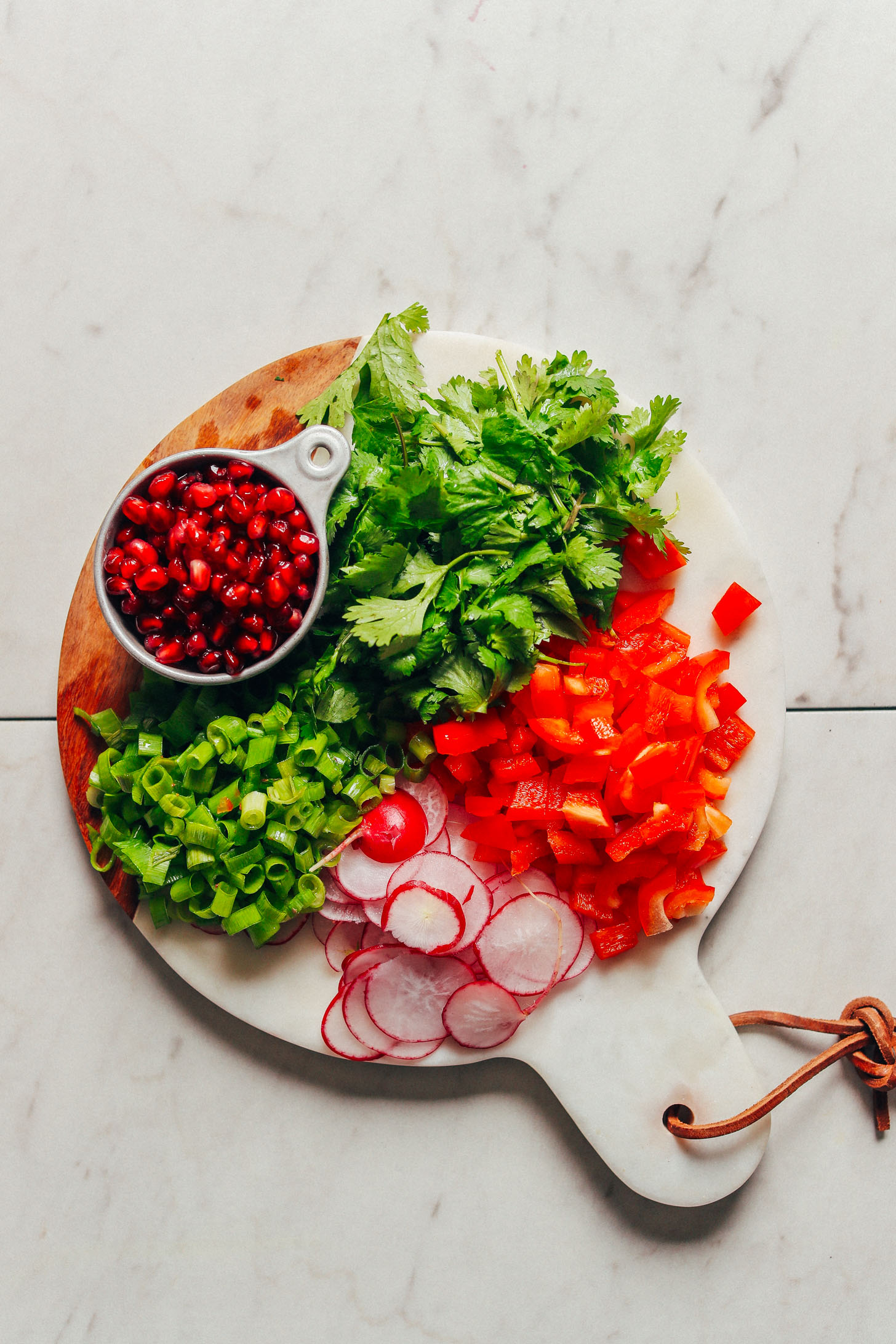 Freshness abounds in this photo of green onion, cilantro, pomegranate seeds, sliced radishes, and diced red bell pepper
