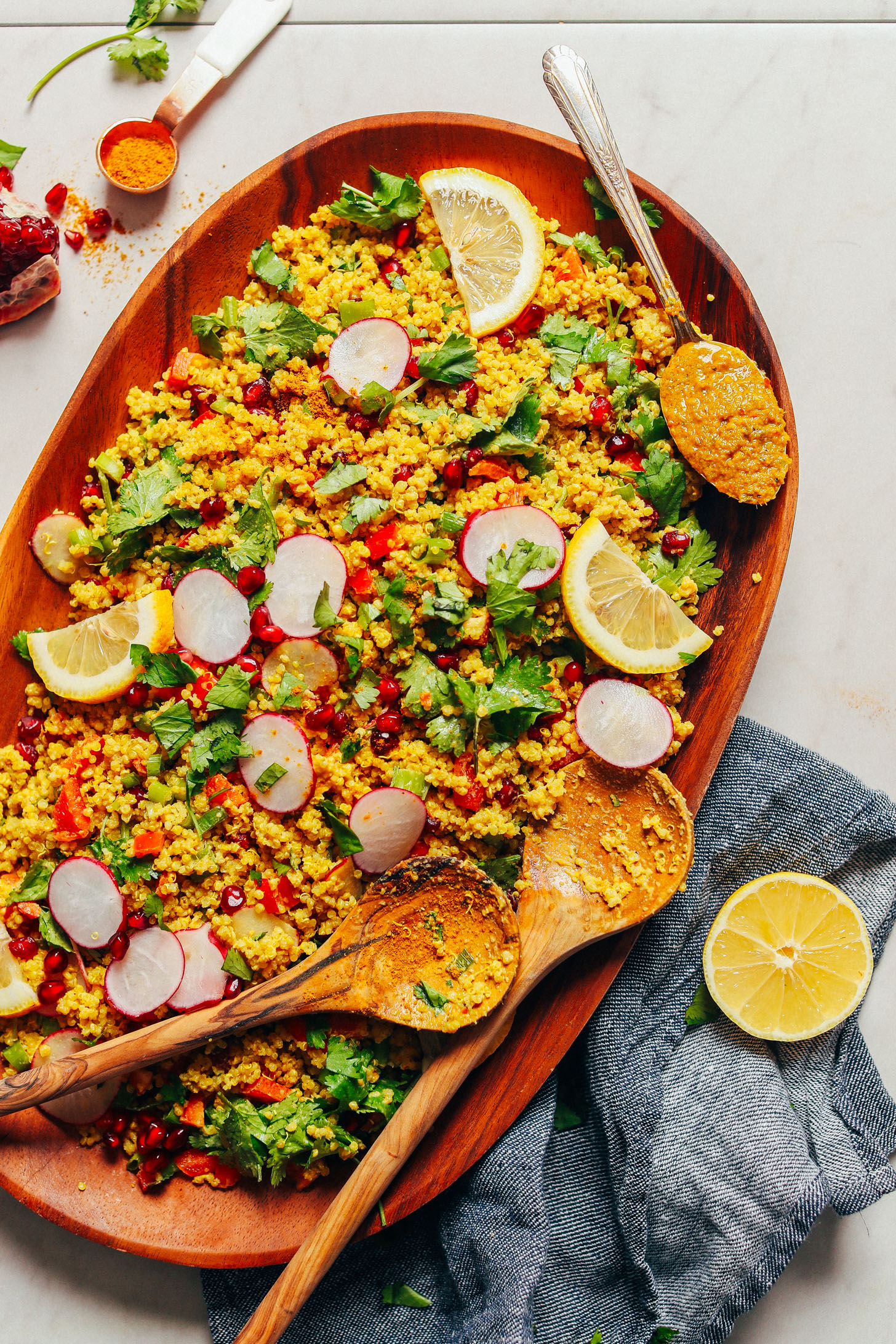 Large wood platter with Curried Quinoa Salad served with fresh vegetables and lemon slices