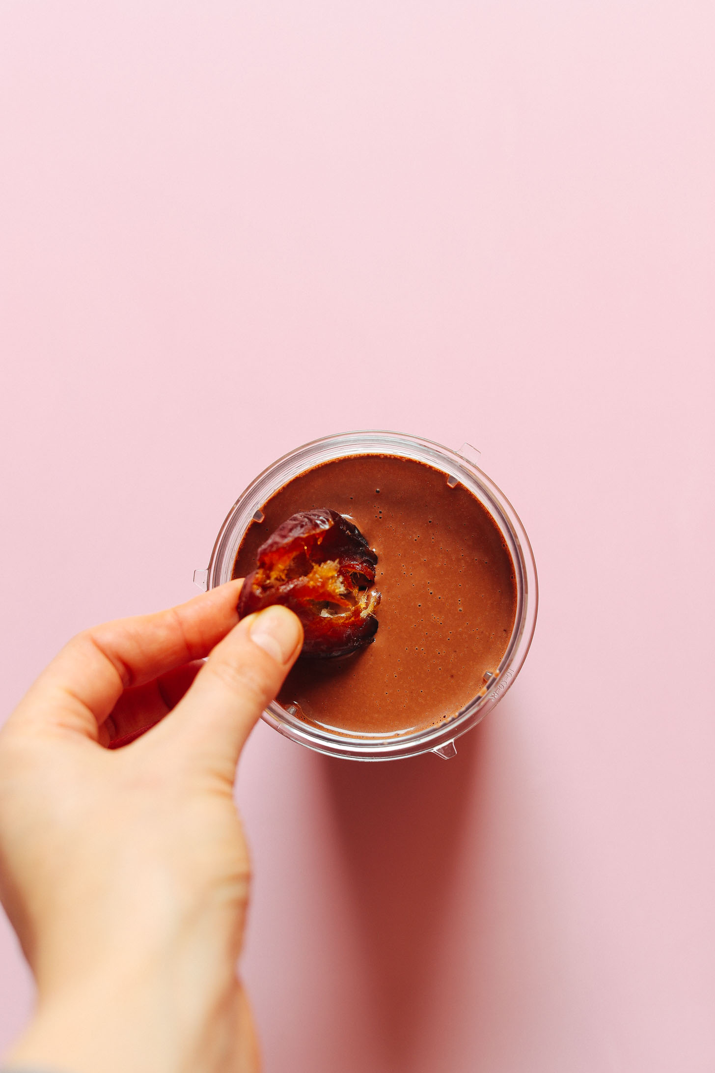 Dipping a freshly pitted date into a jar of Naturally Sweetened Vegan Chocolate Mousse