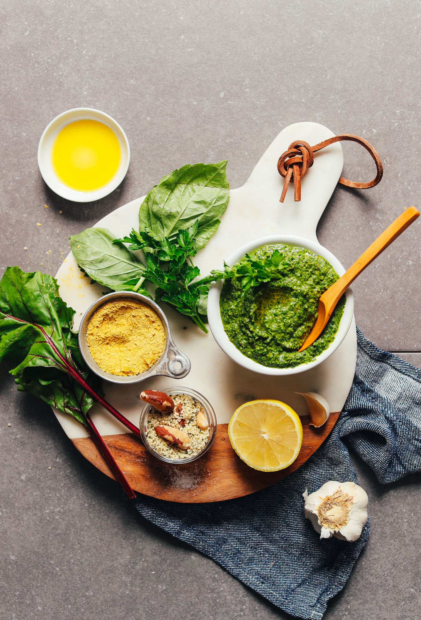 A bowl of pesto surrounded by ingredients used to make it