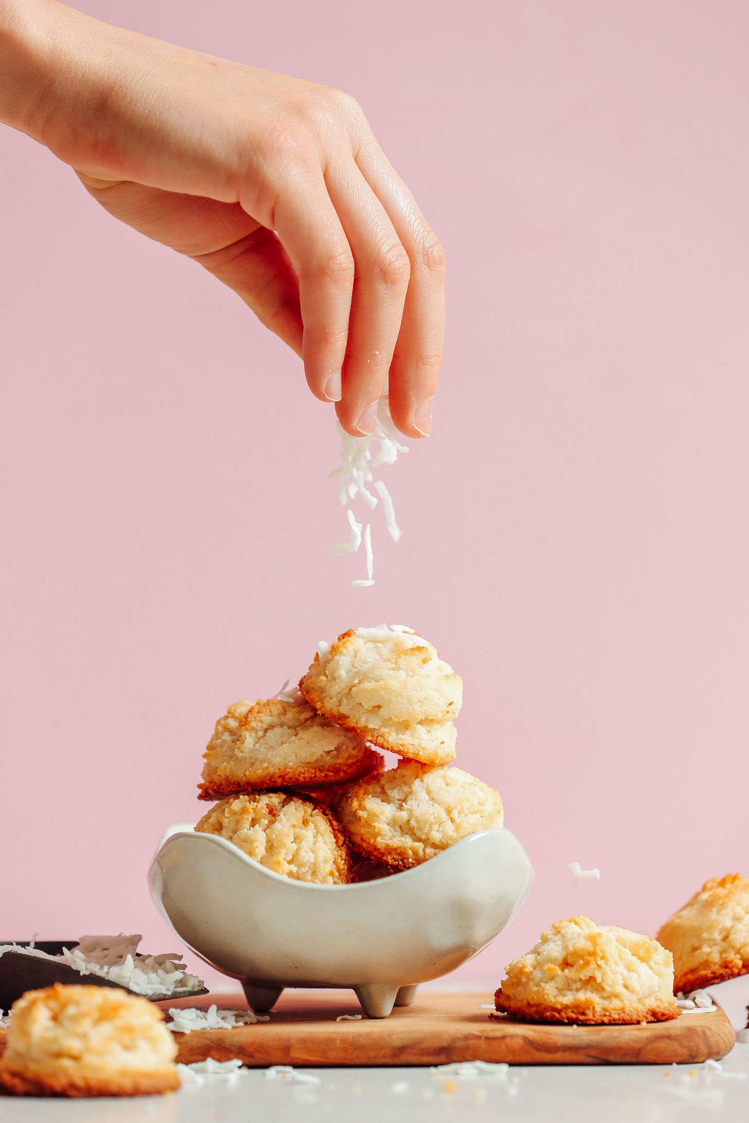 Sprinkling coconut onto a stack of our delicious Vegan Coconut Snowball Cookies