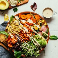 A large salad bowl filled with our Abundance Green Salad with Savory Tahini Dressing- the perfect gluten-free vegan meal