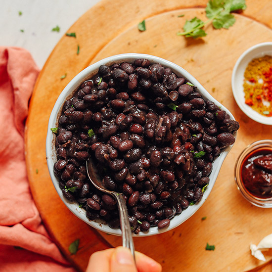 Using a spoon to pick up a serving of homemade black beans made from scratch
