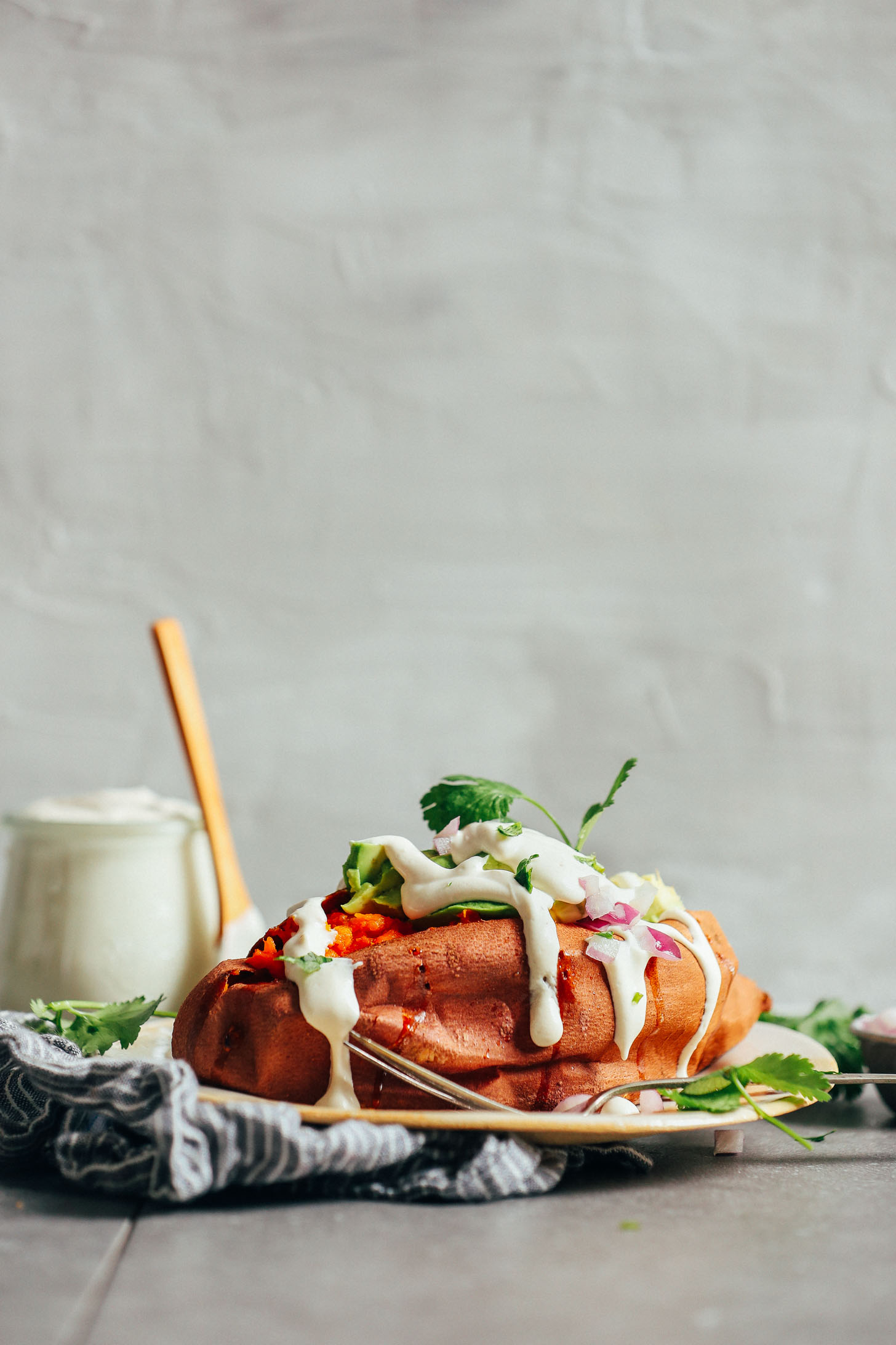 Baked sweet potato loaded with fresh vegetables and topped with homemade vegan sour cream