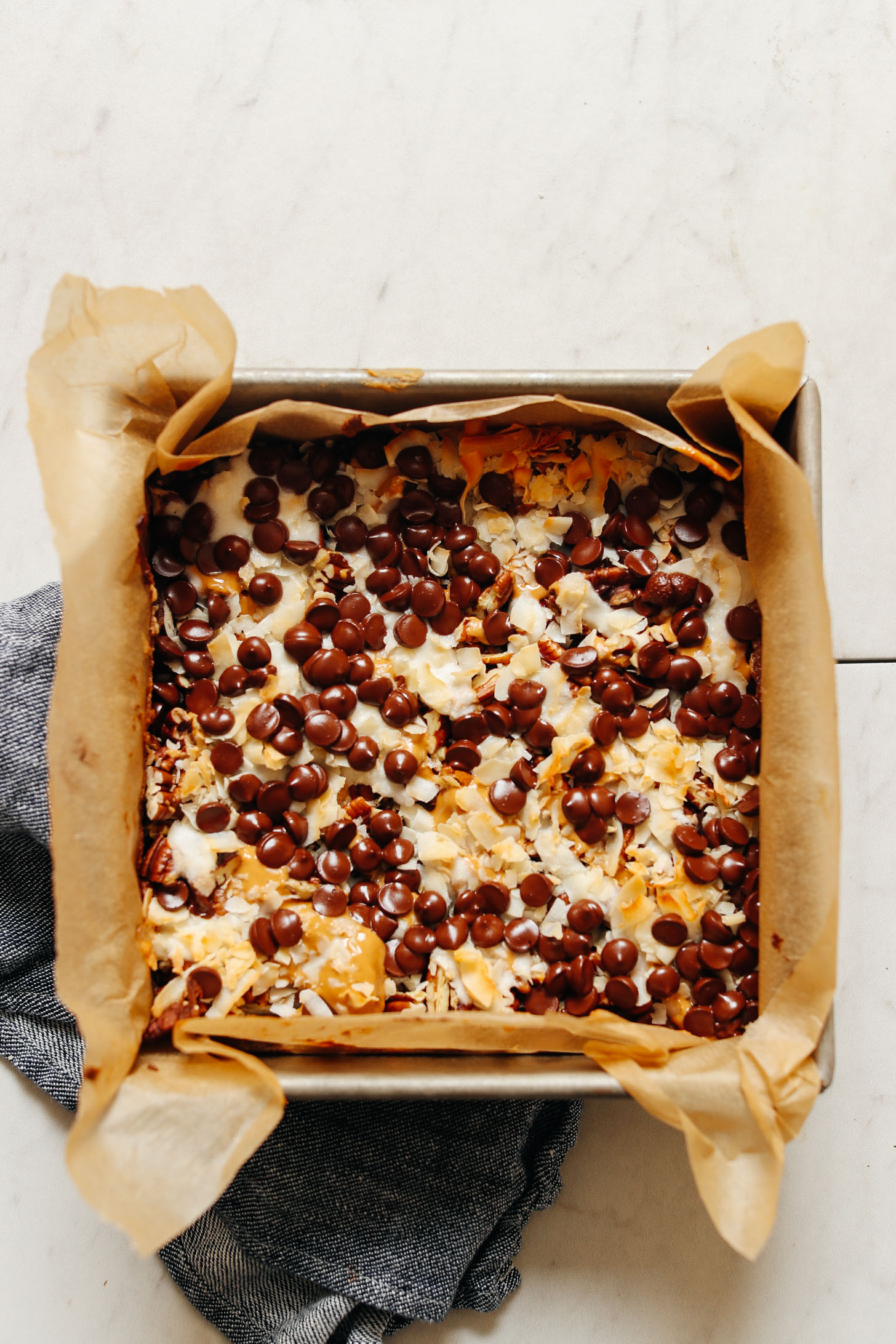Parchment-lined baking pan filled with a batch of gluten-free Vegan 7-Layer Bars