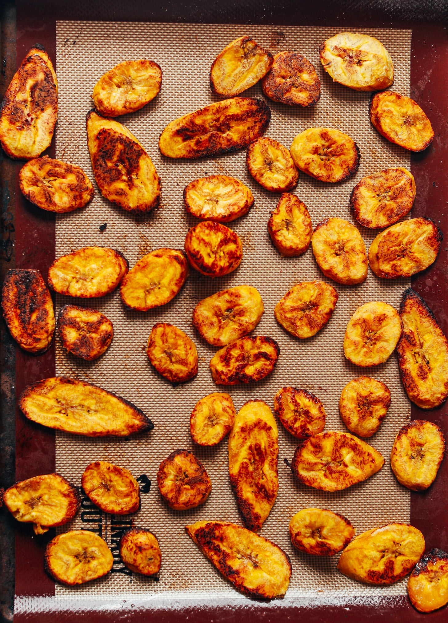 Freshly roasted, perfectly browned plantains on a silicone-lined baking sheet