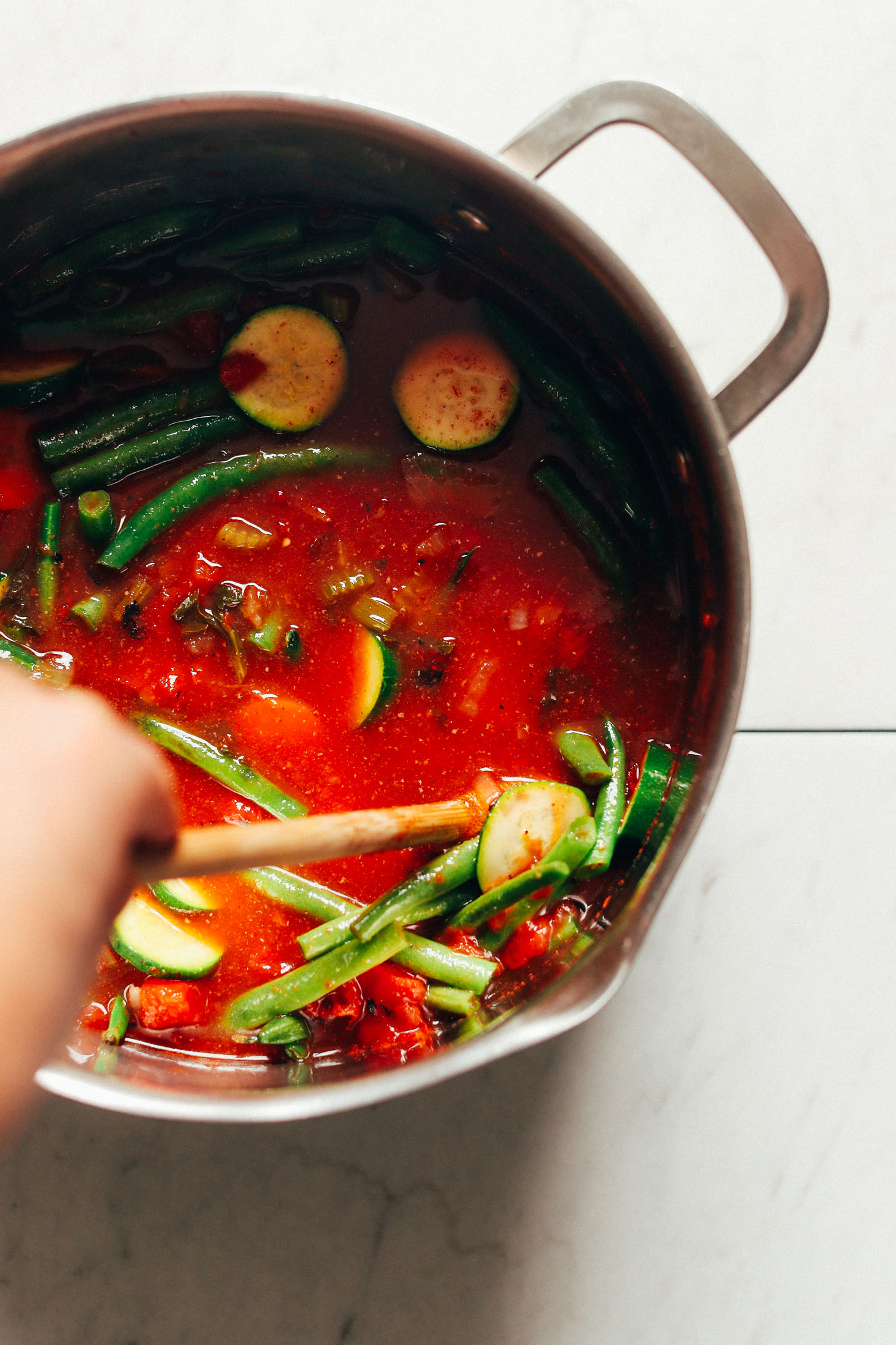 Stirring in green beans, zucchini, fire-roasted tomatoes, kale, and vegetable broth into our nourishing Fire-Roasted Tomato Veggie Mung Bean Soup