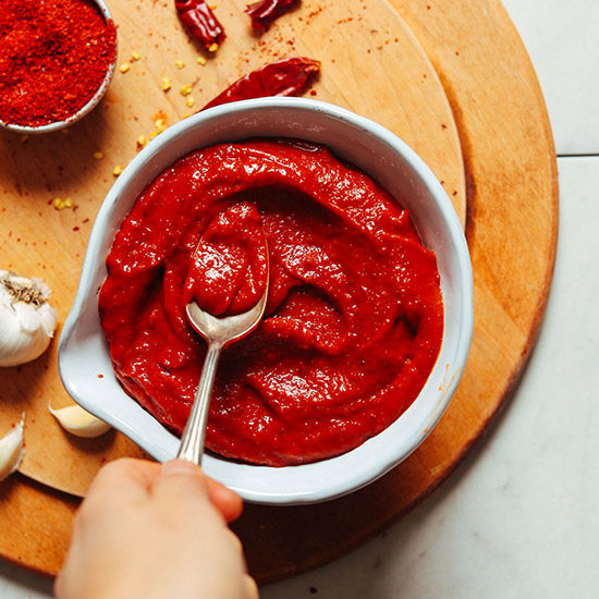 Using a spoon to smooth the top of a bowl of Korean-Inspired homemade Gochujang sauce