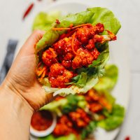 Holding a lettuce leaf stuffed with gluten-free and vegan Korean-Spiced Cauliflower Wings