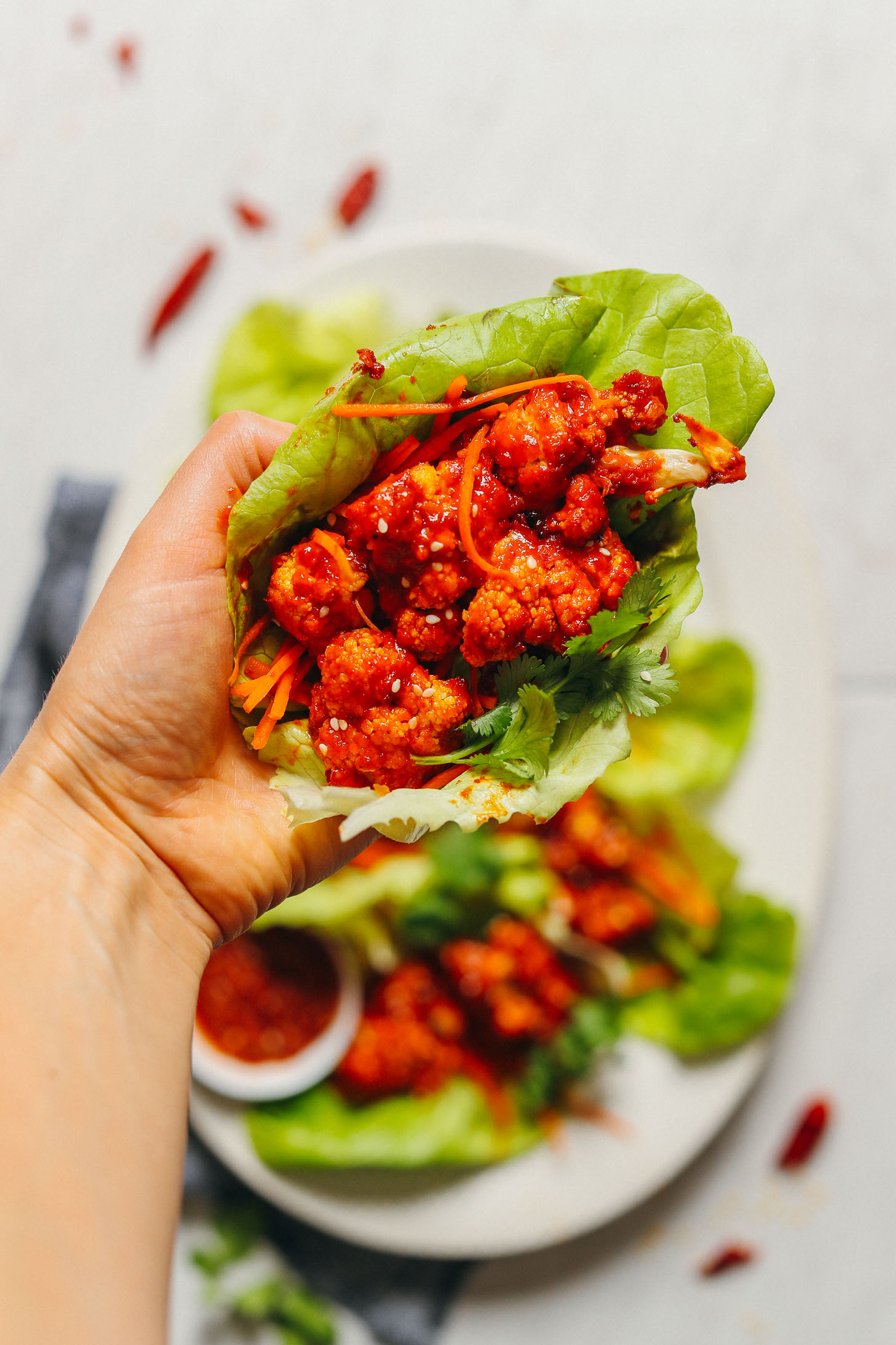 Holding a lettuce leaf stuffed with gluten-free and vegan Korean-Spiced Cauliflower Wings
