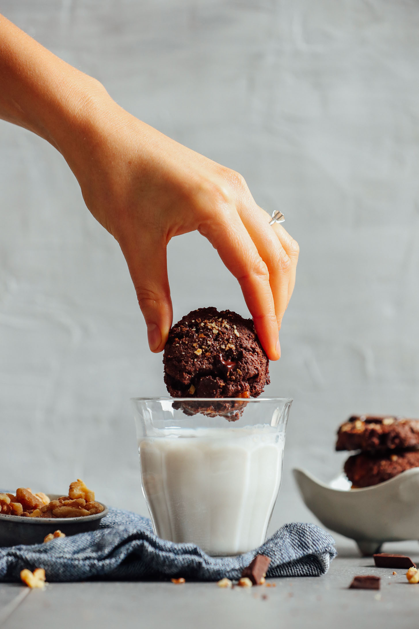Dipping a decadent Vegan Brownie Cookie into a glass of almond milk